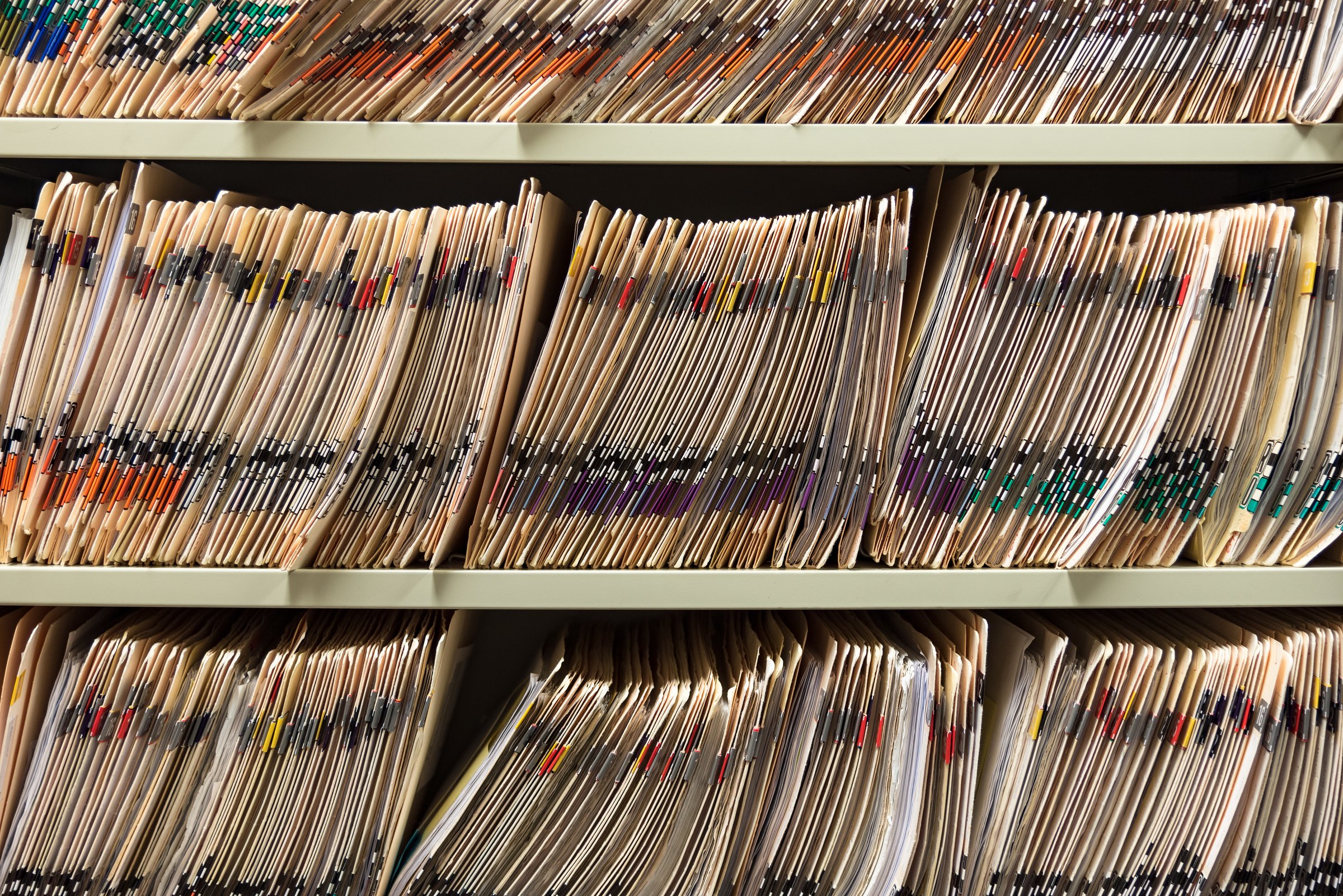 Rows of color-coded paper case files organized on office shelving