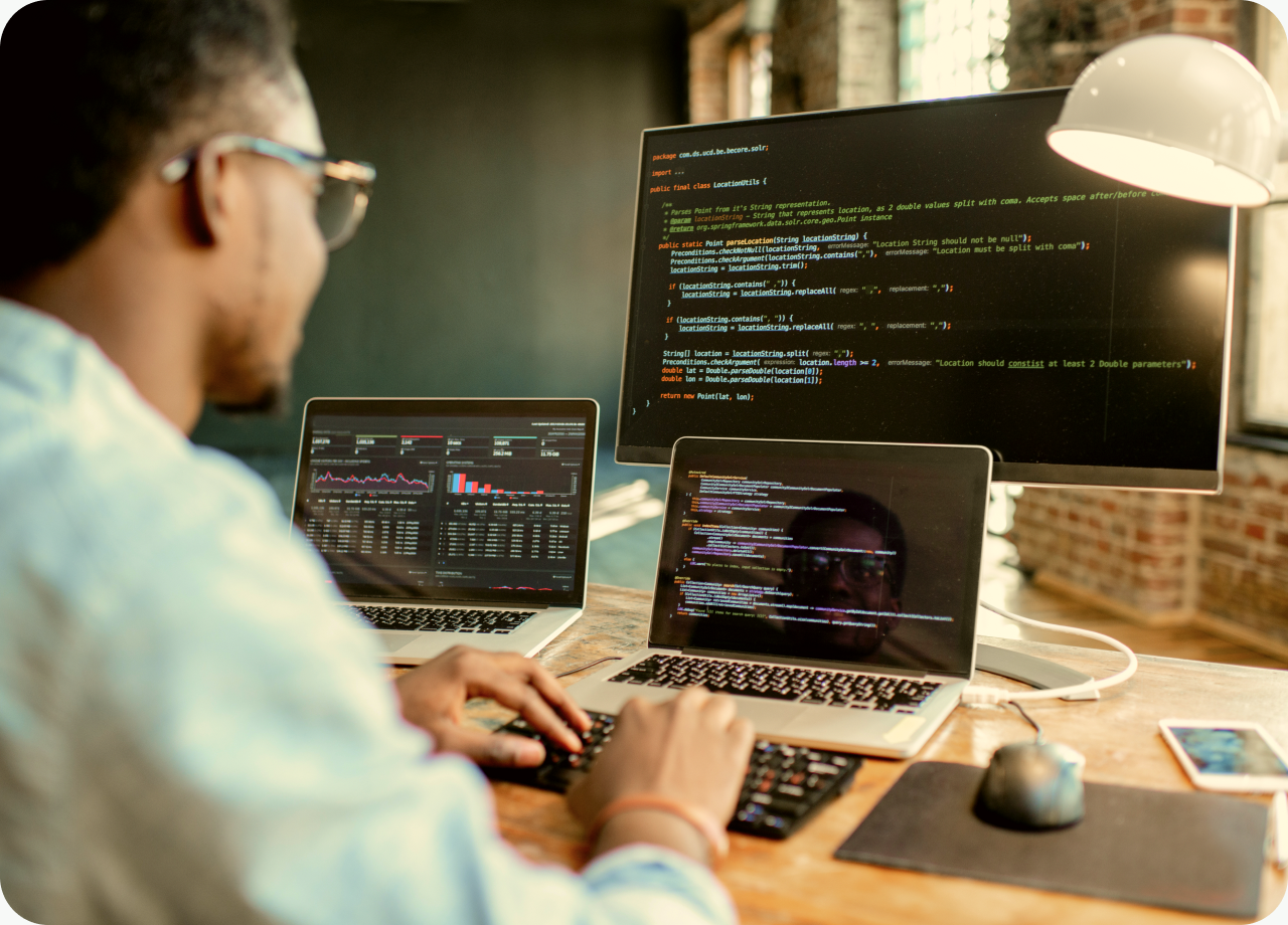 Professional working at a desk with multiple computers.