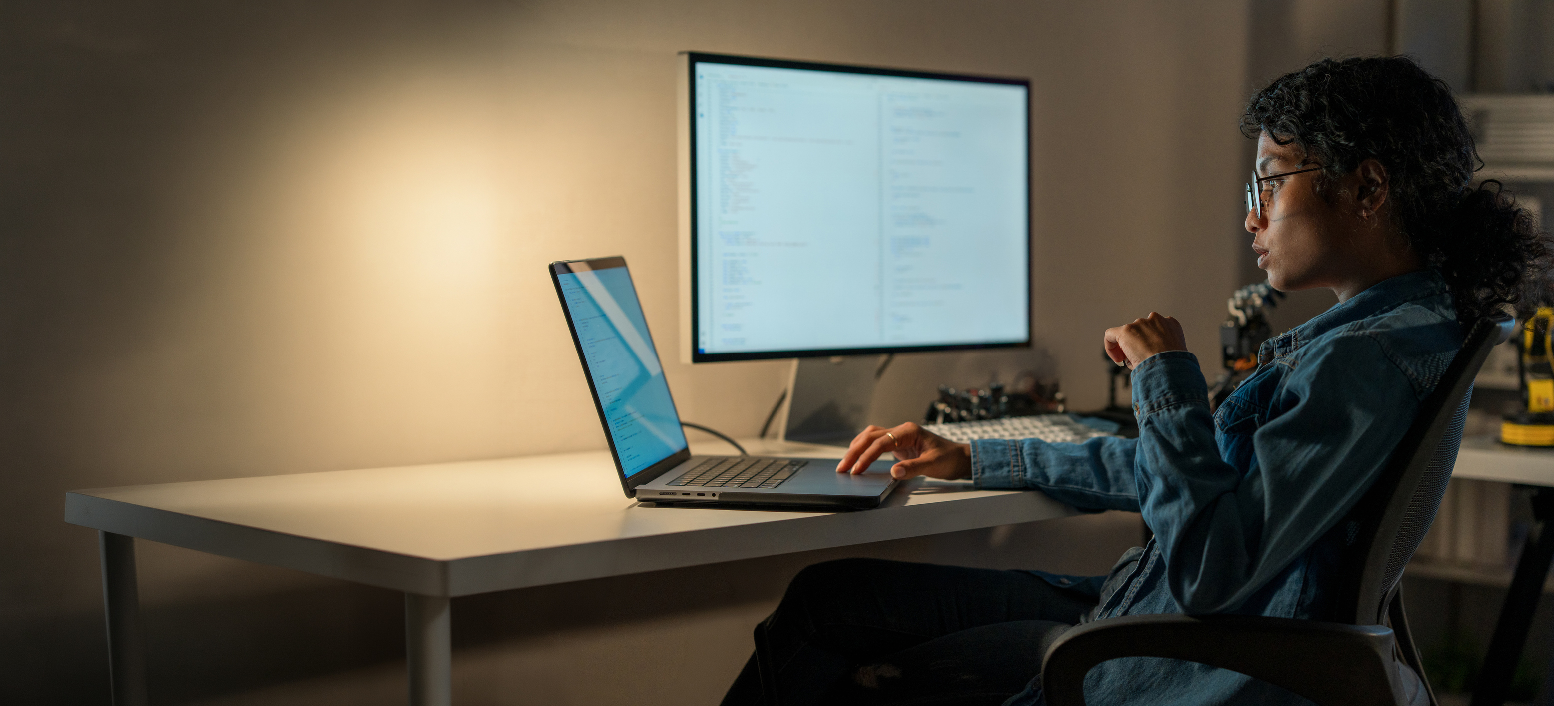 Technology professional working at a desk with a laptop and external monitor.
