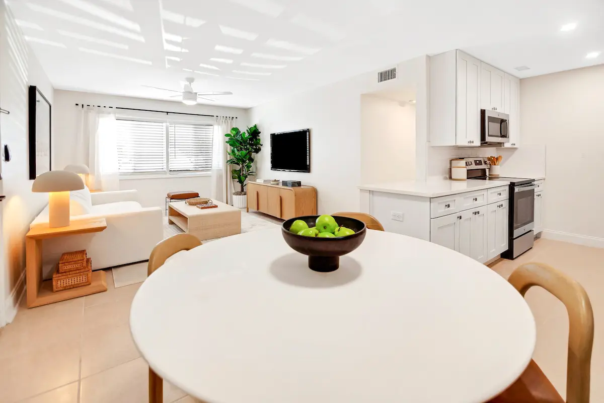 Contemporary dining room off of living room with a large window, potted plant, and minimalist decor.