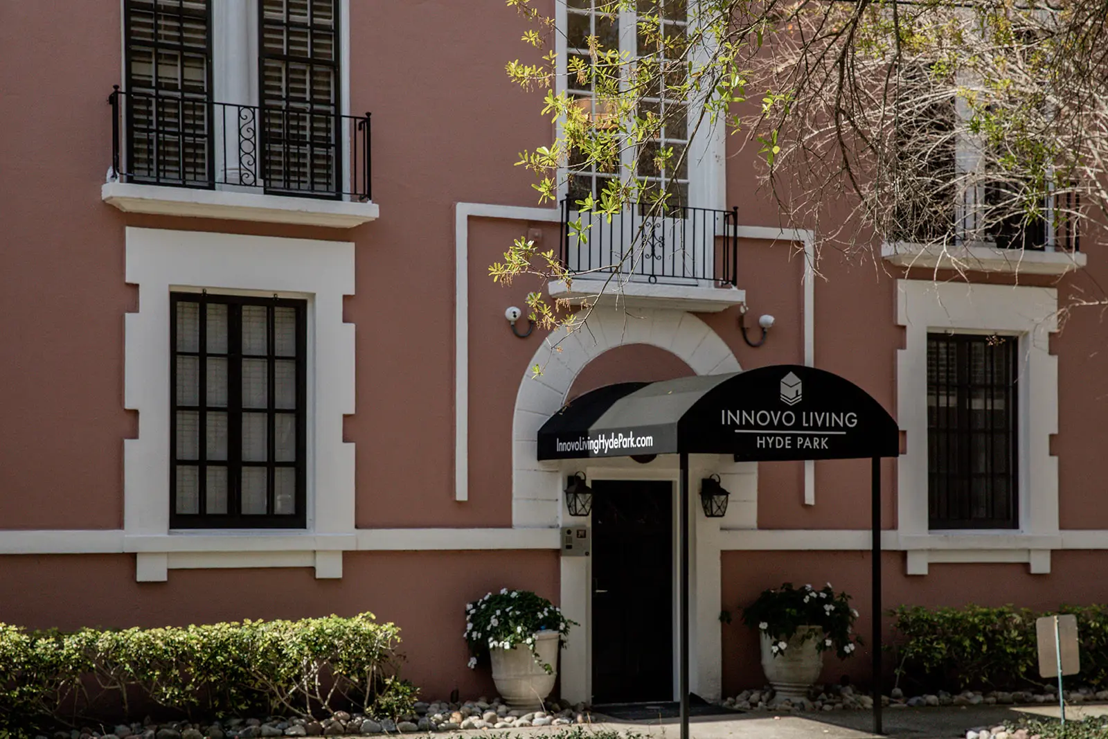 Pink Clewis exterior with black awning and lush green bushes.