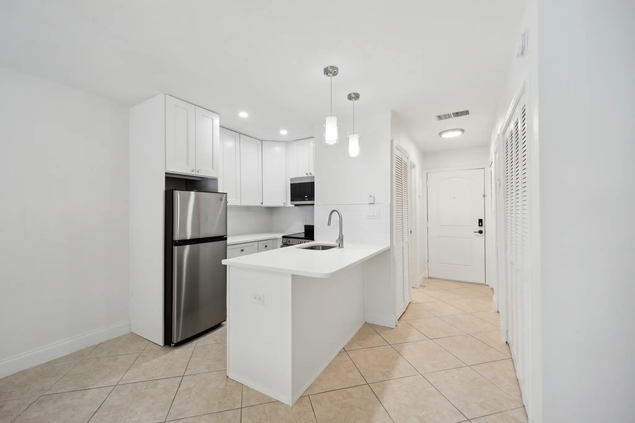  Spacious studio apartment with modern kitchen with white cabinets and stainless steel appliances.