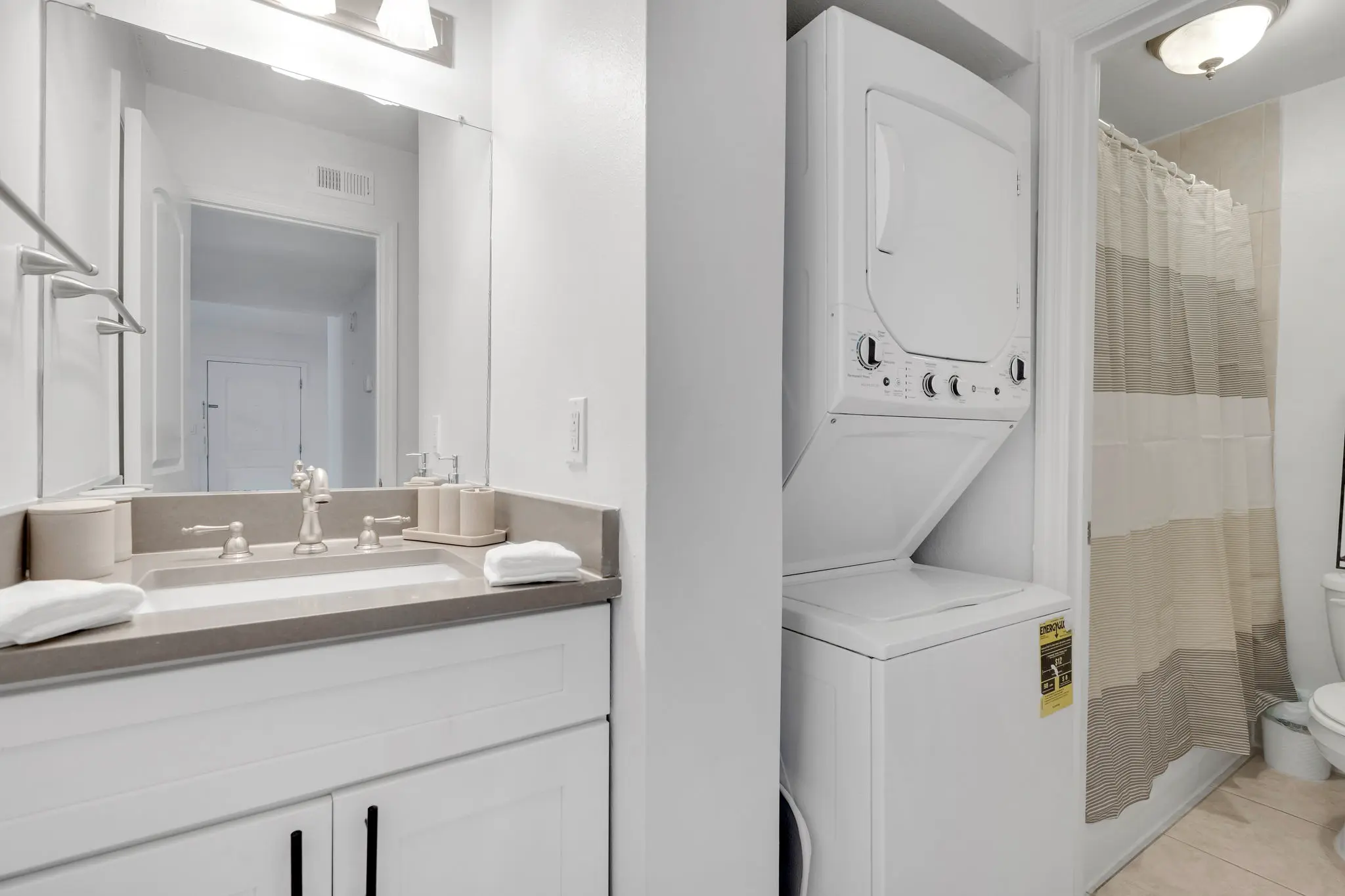 Modern white bathroom with sink, vanity, and in-unit washer/dryer combo.