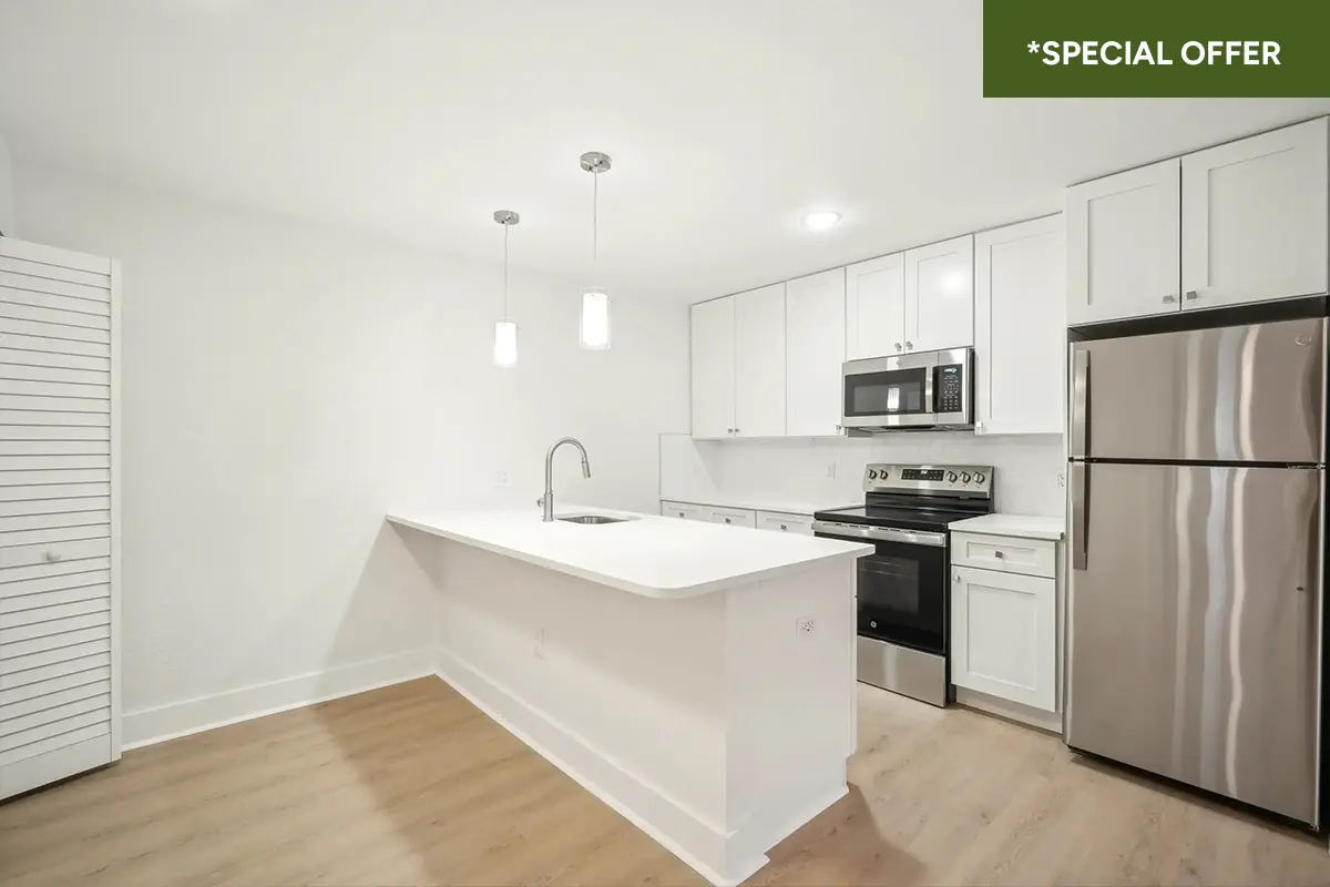 Modern kitchen with granite countertop, white cabinets, breakfast bar, and stainless steel applianes including dishwasher, microwave, range, and refirigerator with text overlay stating "*special offer."