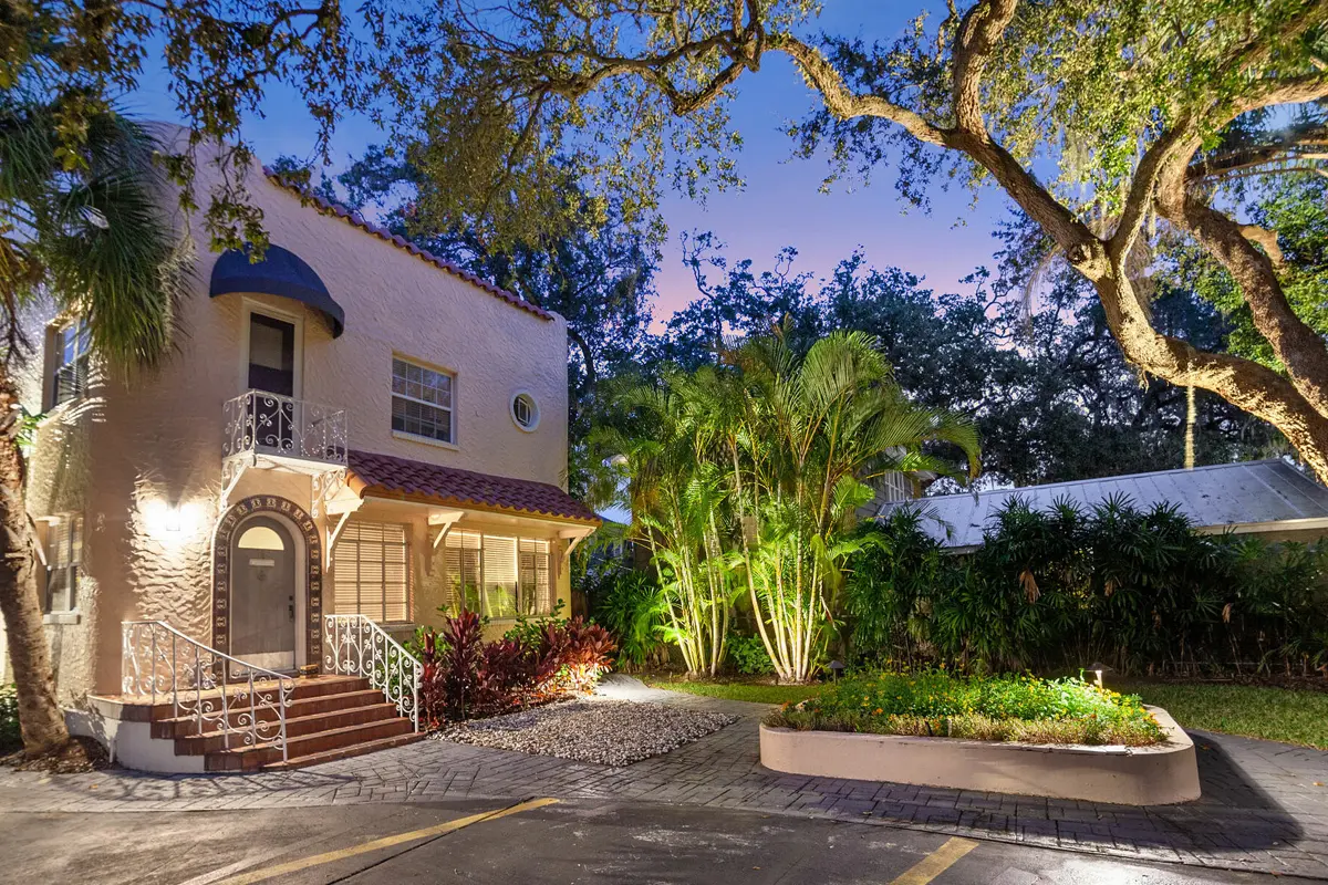 Gorgeous creme colored Dekle exterior in twilight with lush green palms in the foreground with text overlay stating "*special offer."