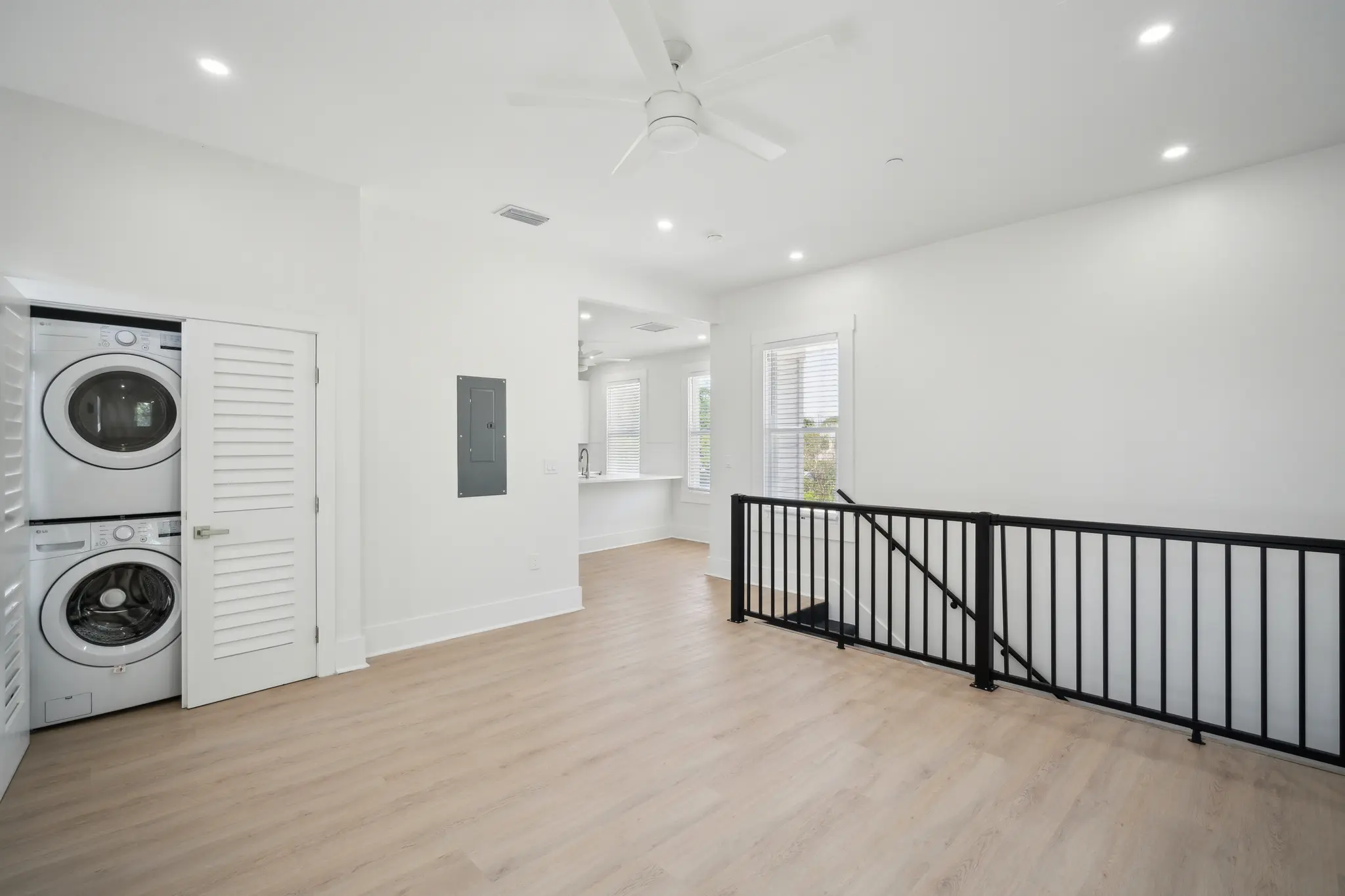 Spacious white living area facing in-unit laundry, window, and staircase.