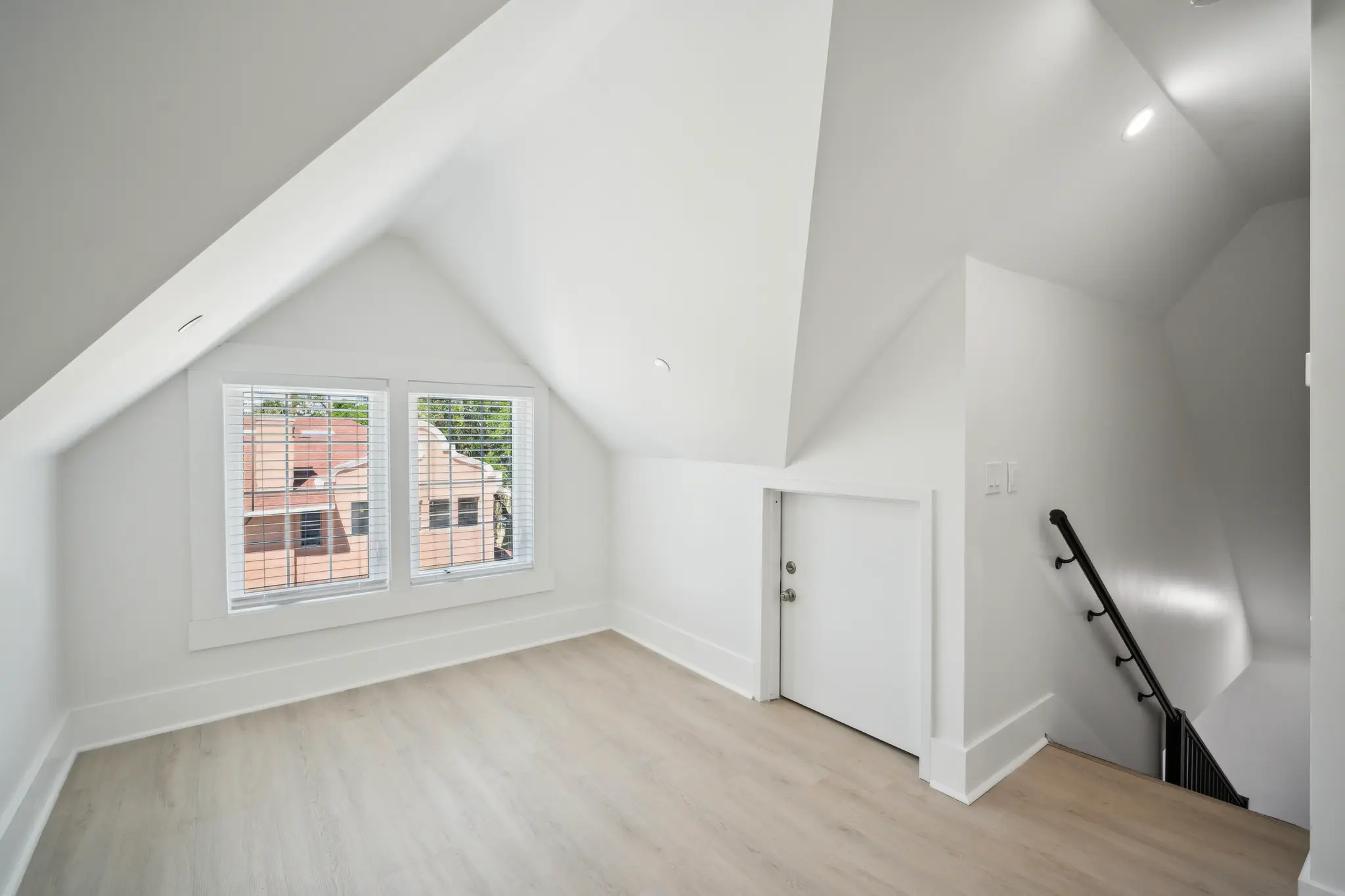 Spacious room with window and staircase.