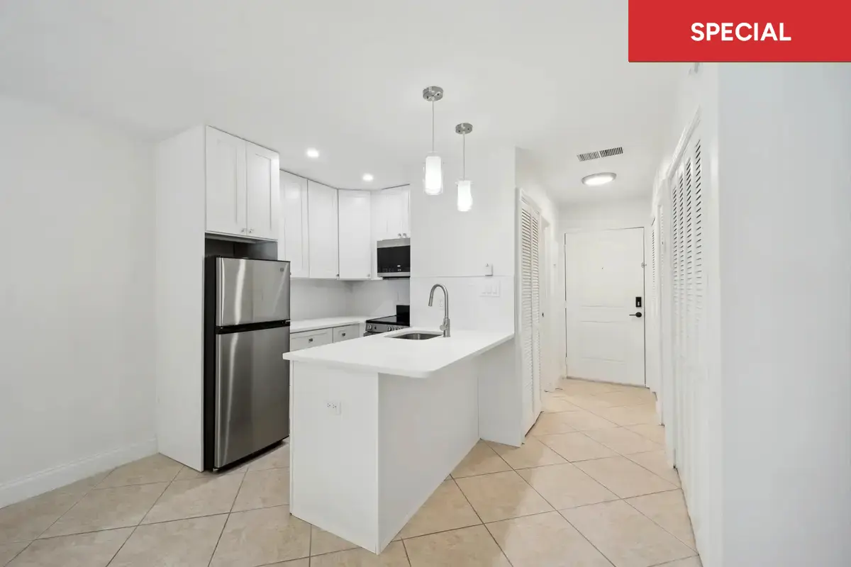 Spacious studio apartment with modern kitchen with white cabinets and stainless steel appliances with overlay stating "special."