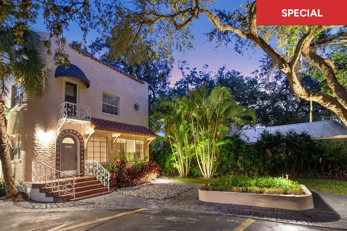 Gorgeous creme colored Dekle exterior in twilight with lush green palms in the foreground with text overlay stating "special."