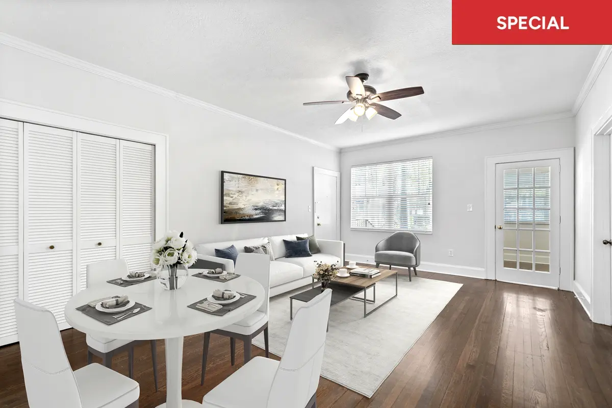 Modern open-plan living and dining room with white furniture, hardwood floors, ceiling fan, and large windows with text overlay stating "special."