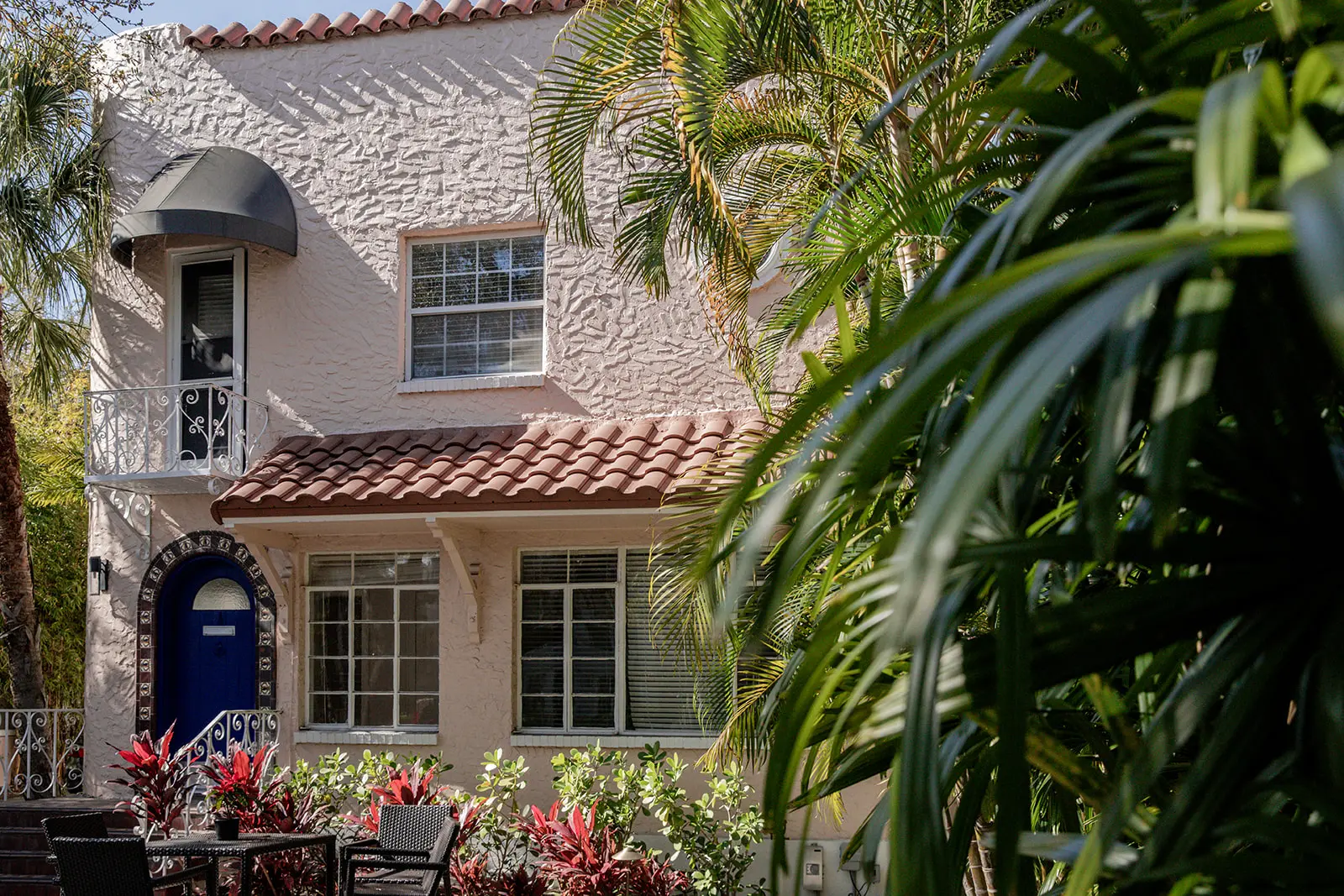 Gorgeous creme colored Dekle exterior with lush green palms in the foreground.