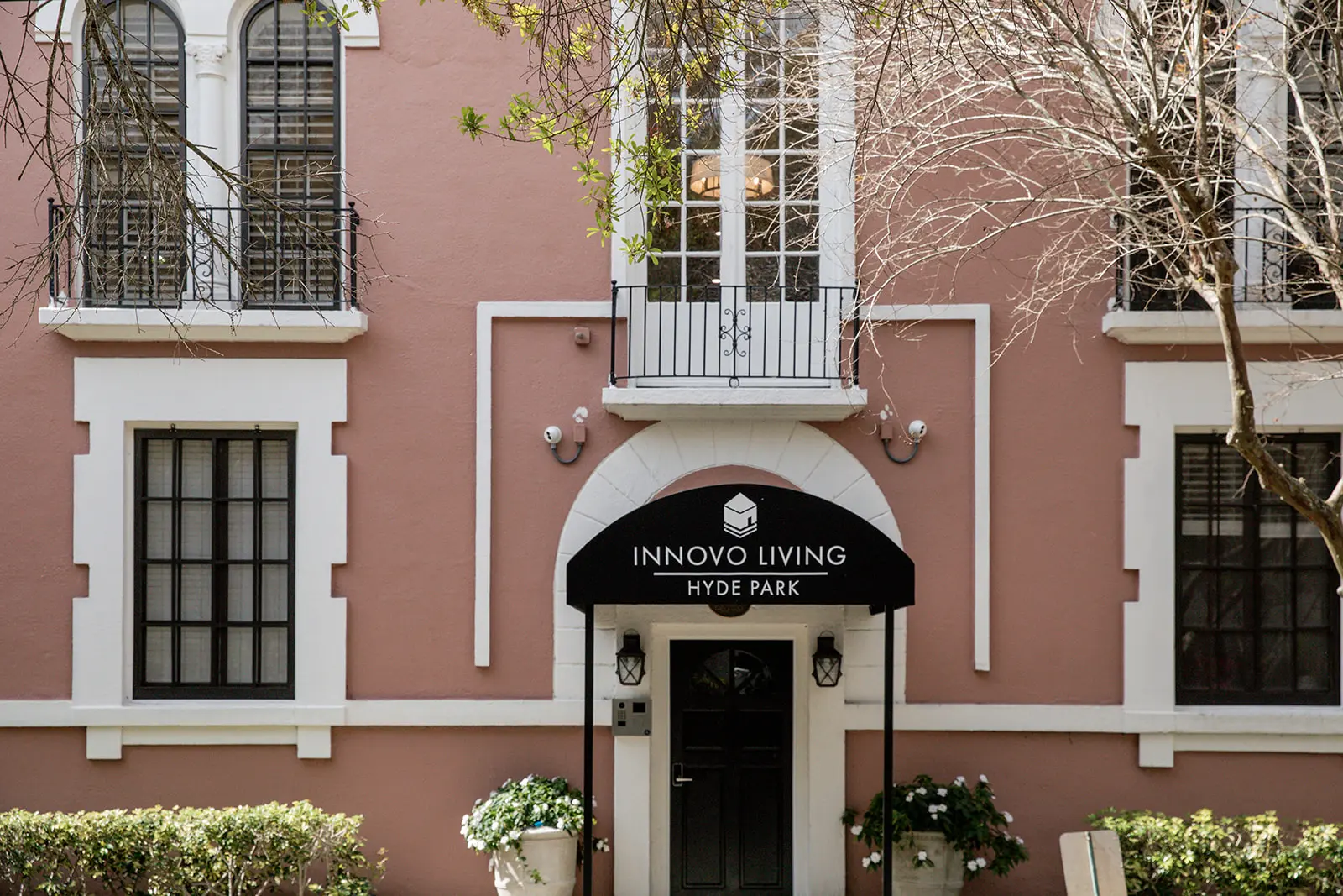 Pink Clewis exterior with black awning and lush green bushes.