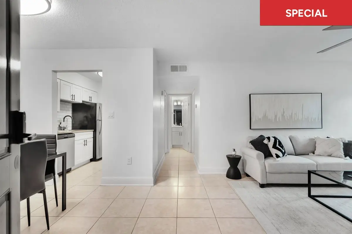 Large living room staged with neutral color furniture facing a dining area with table and kitchen and kitchen off to the left with text overlay stating "SPECIAL."
