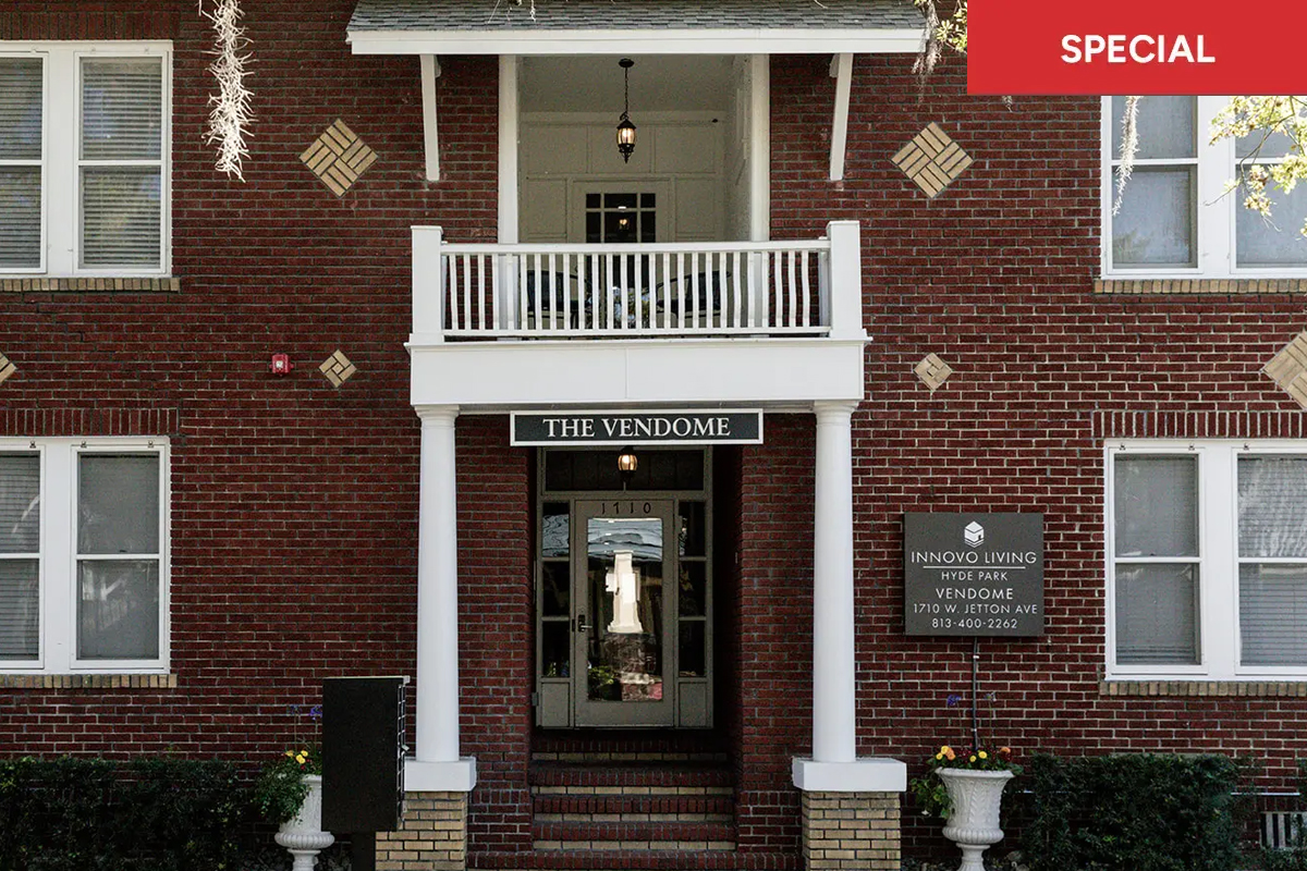 Entrance to The Vendome apartment building at Hyde Park, featuring a red brick facade, white columns with text overlay stating "special."