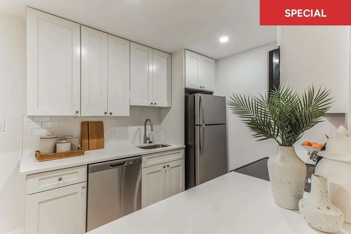 Modern kitchen and dining area with white cabinets and countertops, stainless steel appliances, and red banner with text overlay stating "special."