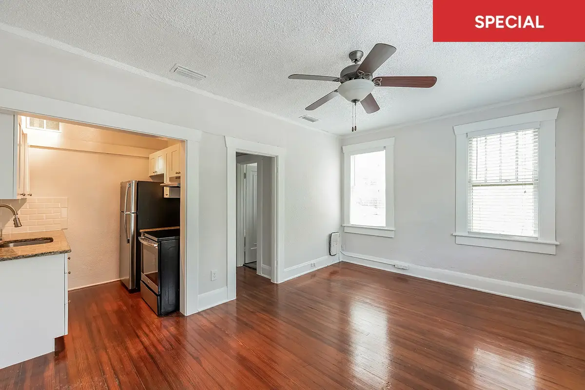 Spacious studio with wood flooring facing windows and modern galley kitchen to the left and red banner with text overlay stating "special."