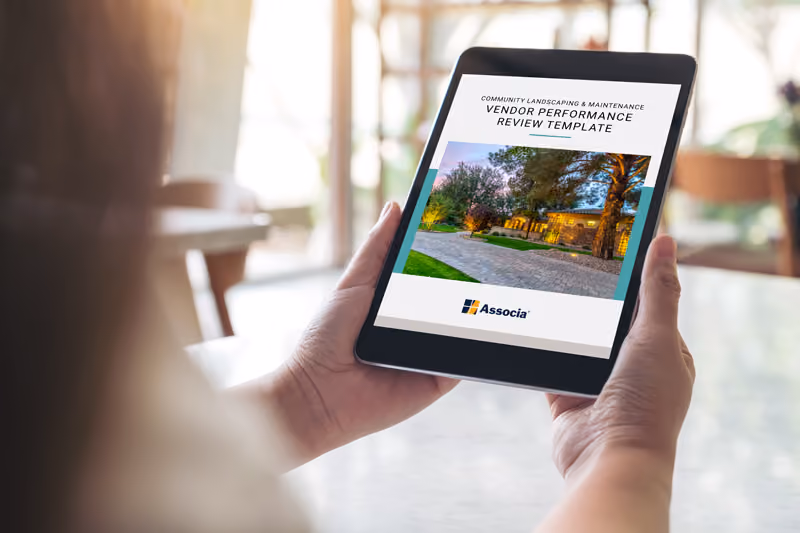 Person holding tablet showing vendor performance review template for community landscaping and maintenance.