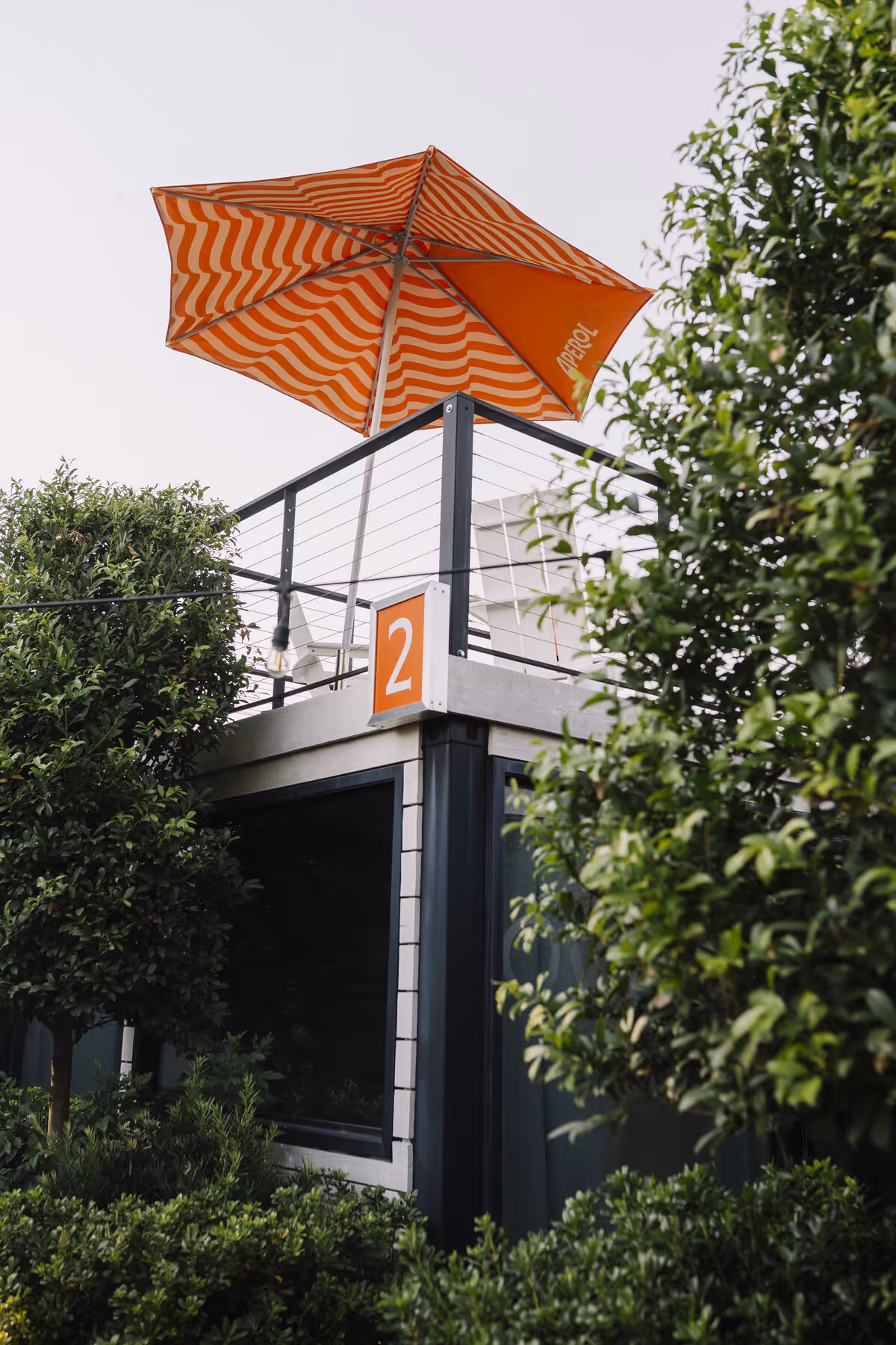 Orange striped Aperol umbrella shading a private rooftop deck above bungalow number two