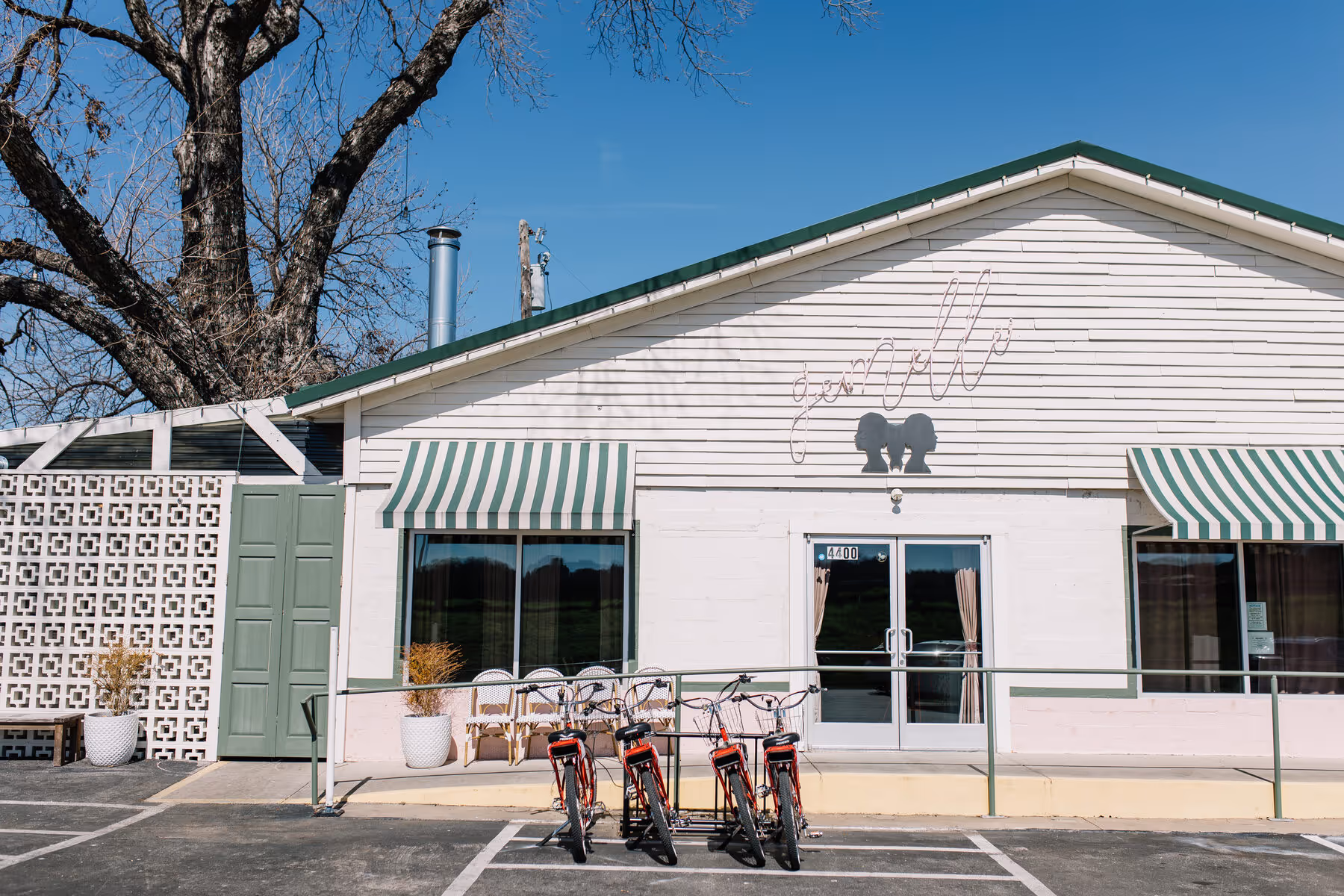 Gemelle restaurant exterior with green-and-white striped awnings and red beach cruiser bicycles parked out front