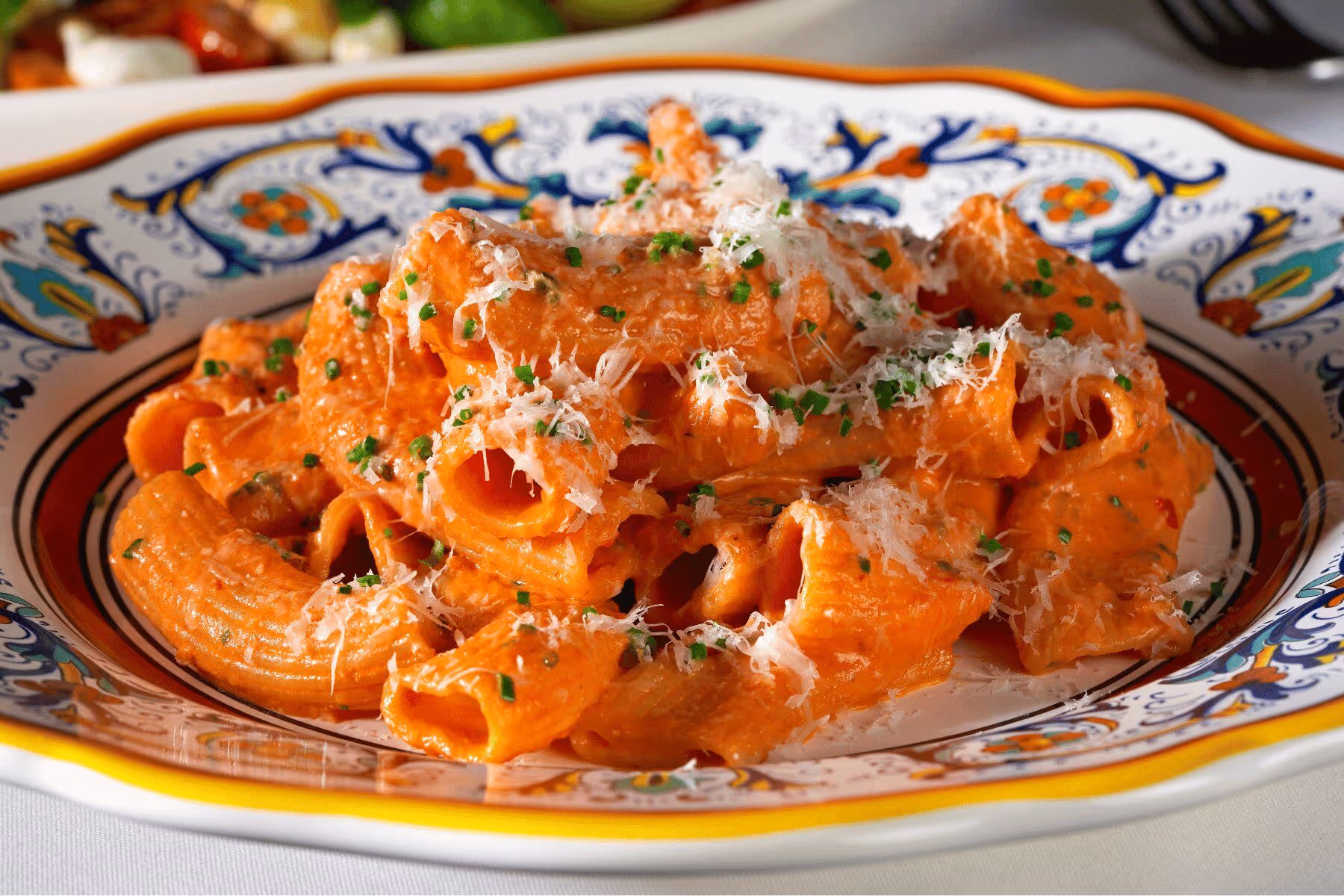 Rigatoni alla vodka with shaved parmigiano and chives in a hand-painted Italian ceramic bowl at Gemelle