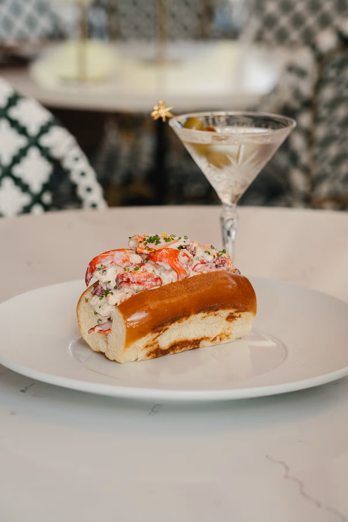Lobster roll on toasted brioche topped with chives and lemon zest, paired with a martini at Stewart's