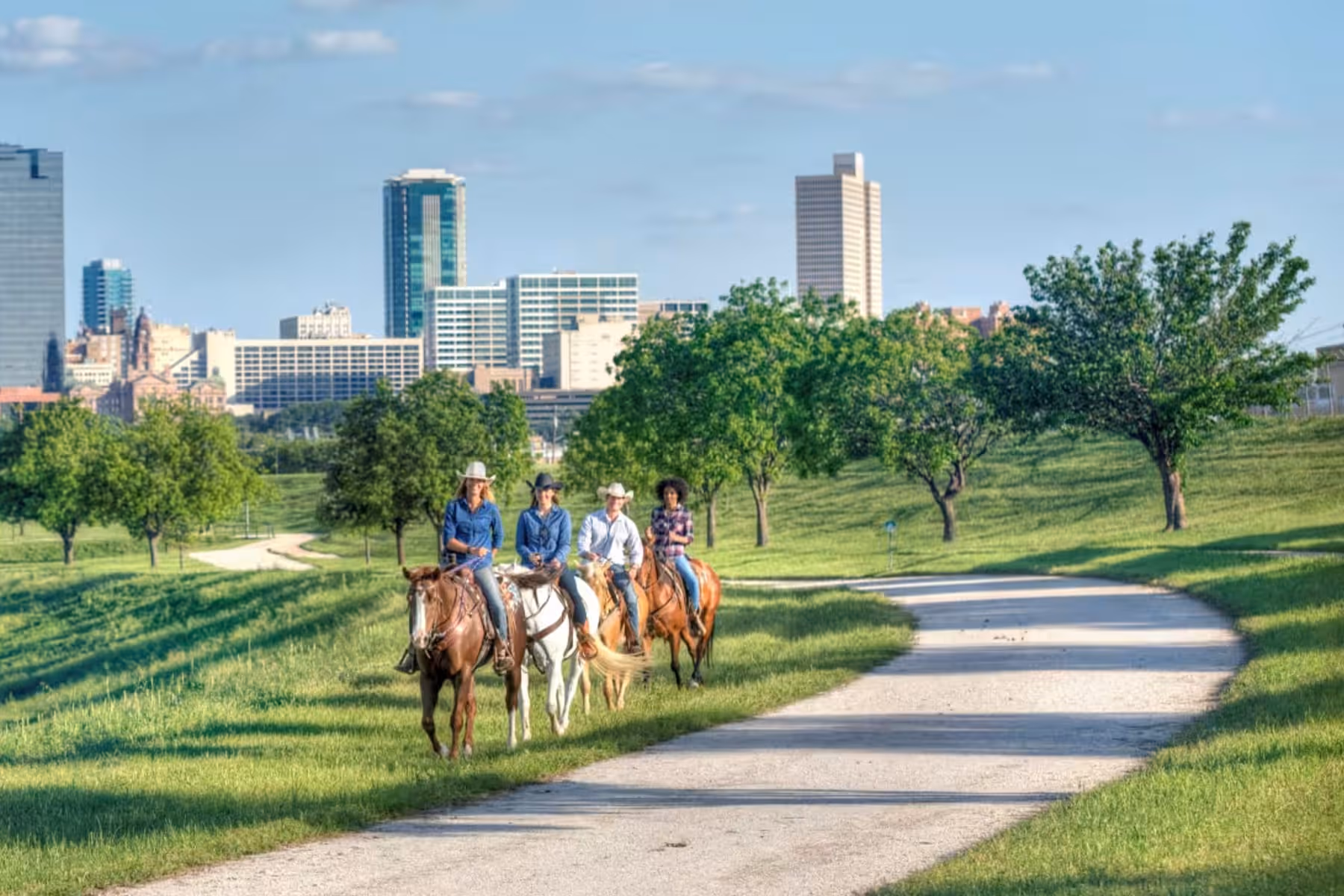 Horseback riders on a Trinity Trails path with the downtown Fort Worth skyline in the background