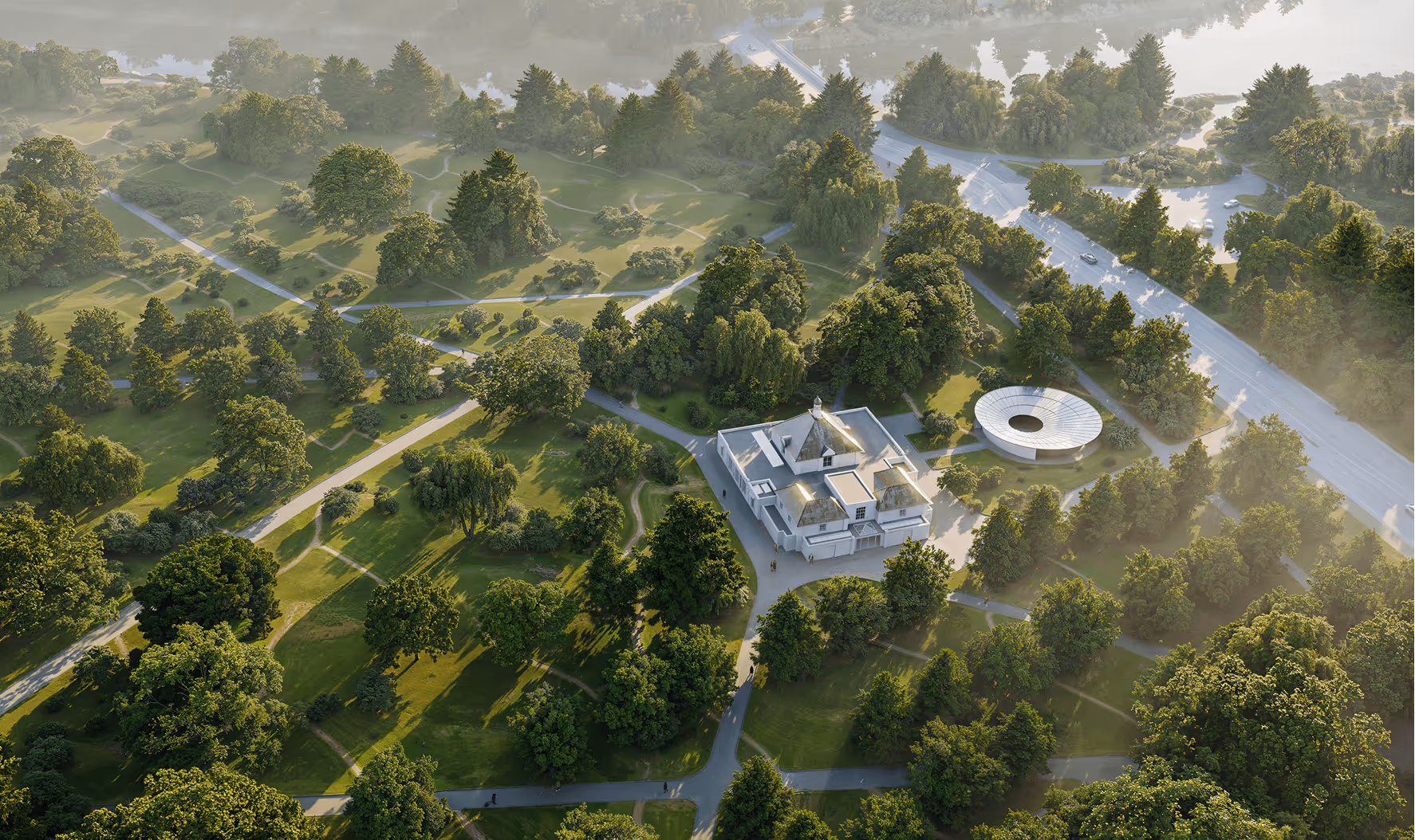 Aerial view of a green park with many trees, intersecting walking paths, a traditional building, and a circular modern structure near a road.
