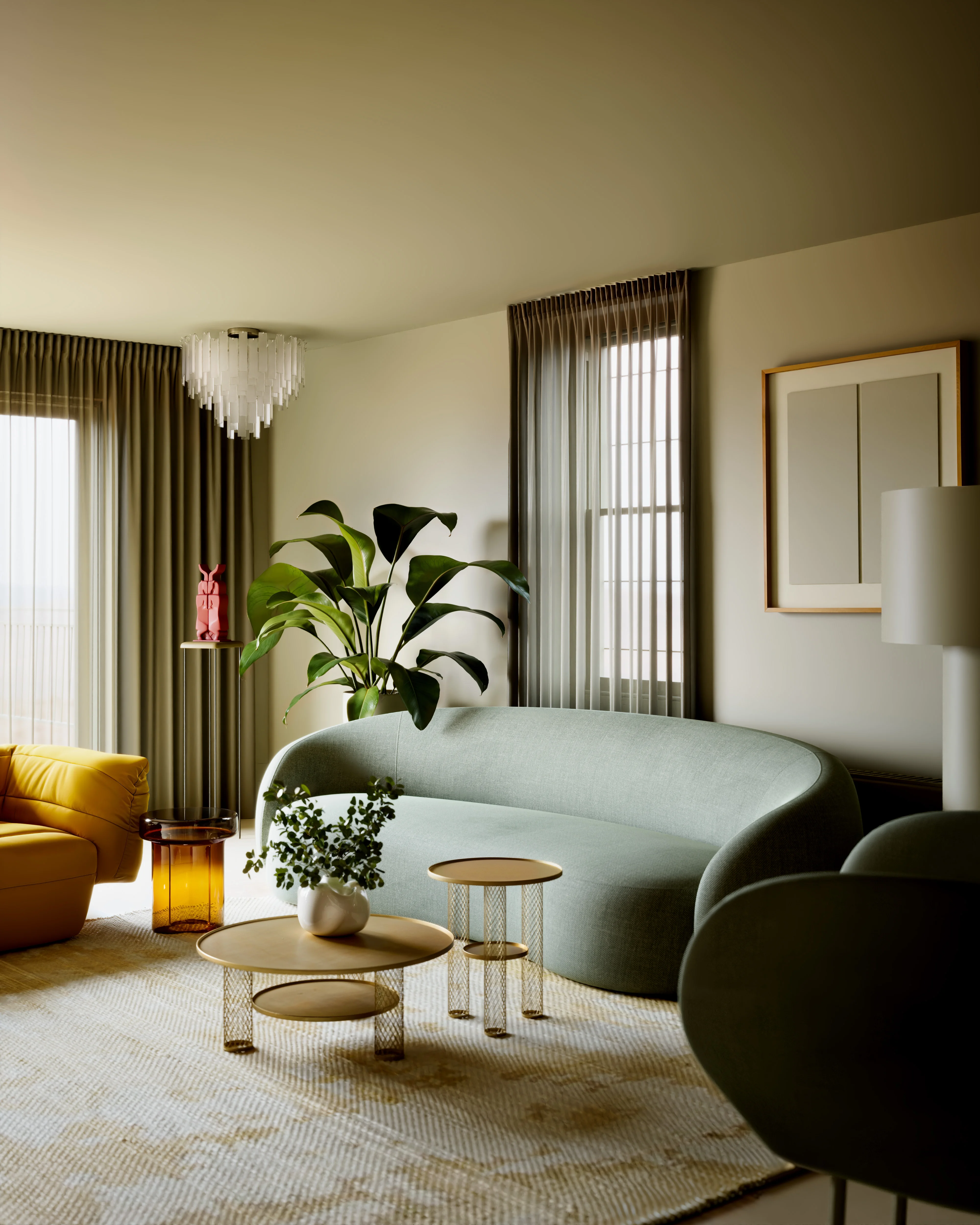 Modern living room with a curved green sofa, yellow armchair, two gold side tables with a plant, large leafy plant, and windows with sheer curtains.
