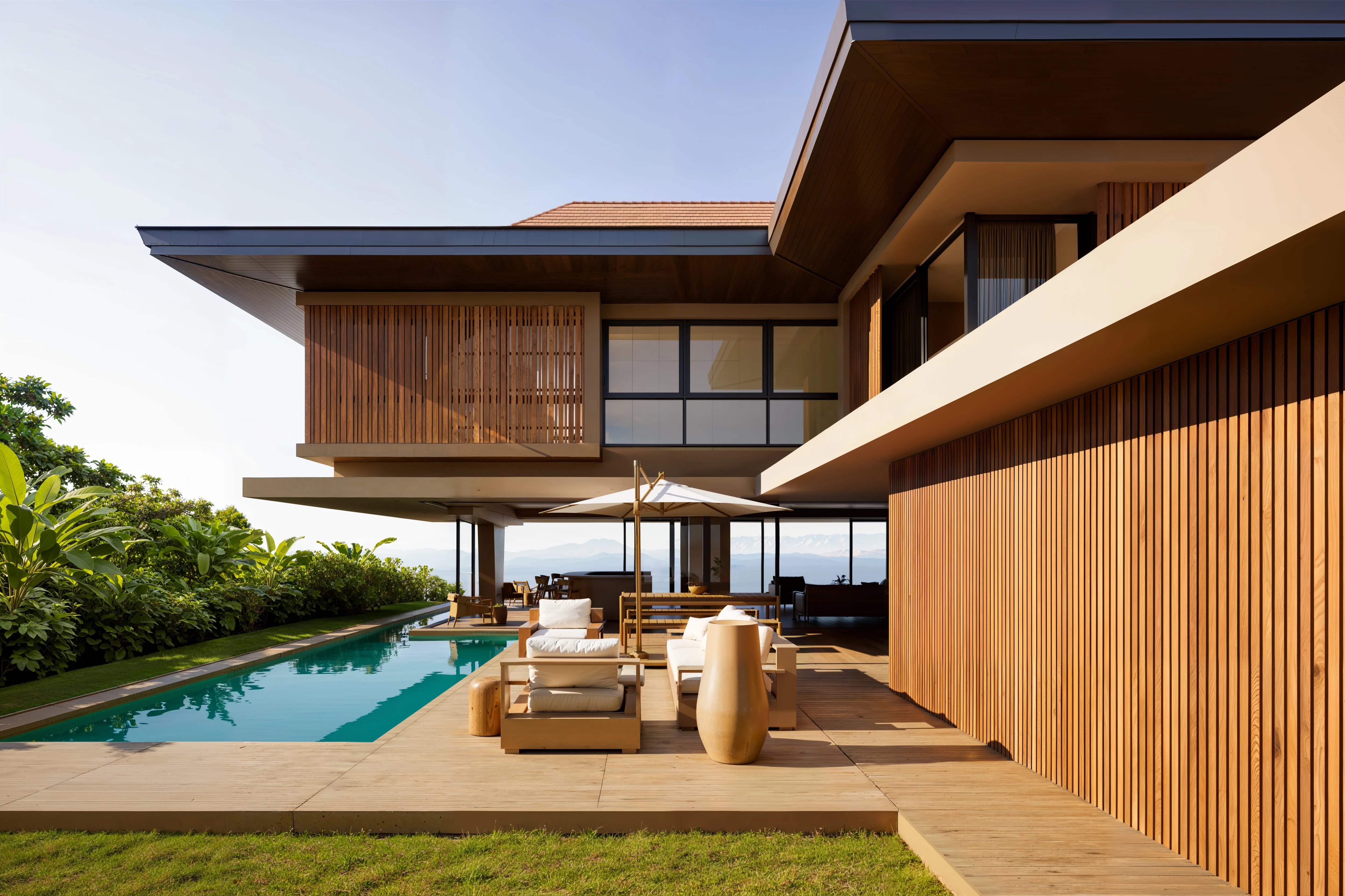 Modern house with wooden paneling, patio furniture, umbrella, and a narrow swimming pool next to green plants under clear sky.