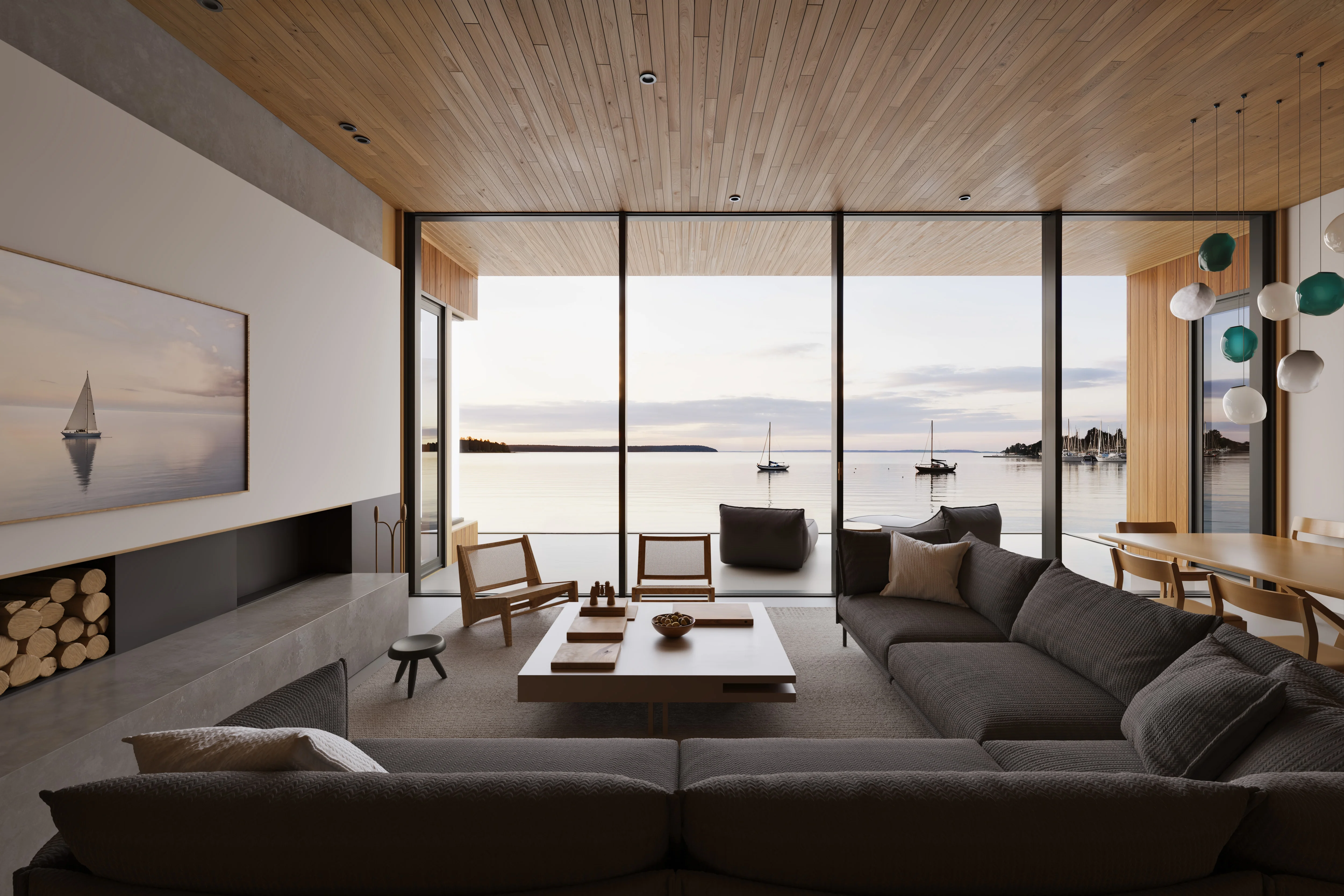 Modern living room with large gray sectional sofa, wooden chairs, coffee table, and floor-to-ceiling windows overlooking calm water with sailboats at sunset.