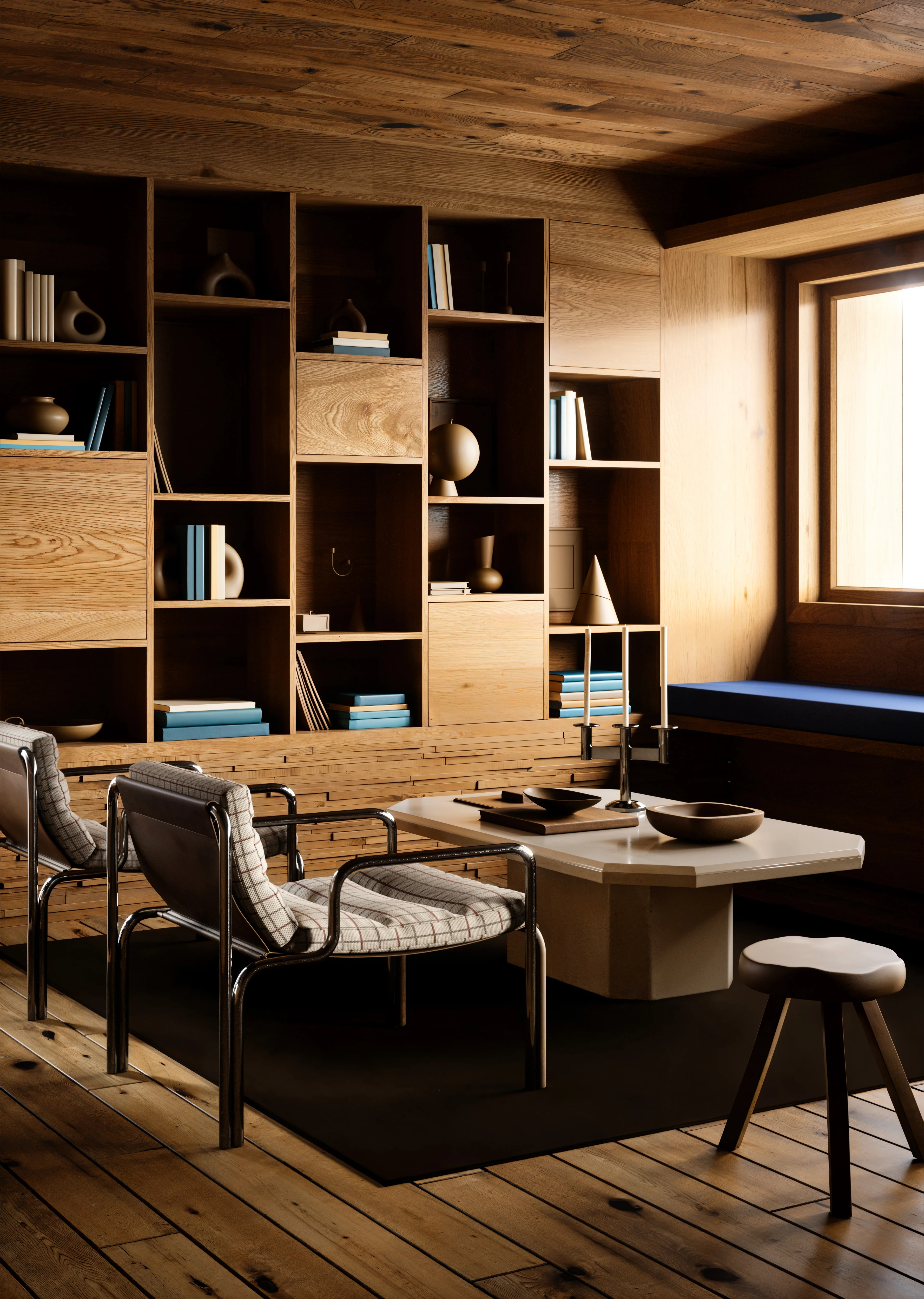Modern wood-paneled room with built-in shelving, two cushioned chairs, a white coffee table with decorative bowls and candles, and a wooden stool near a window bench with blue cushion.