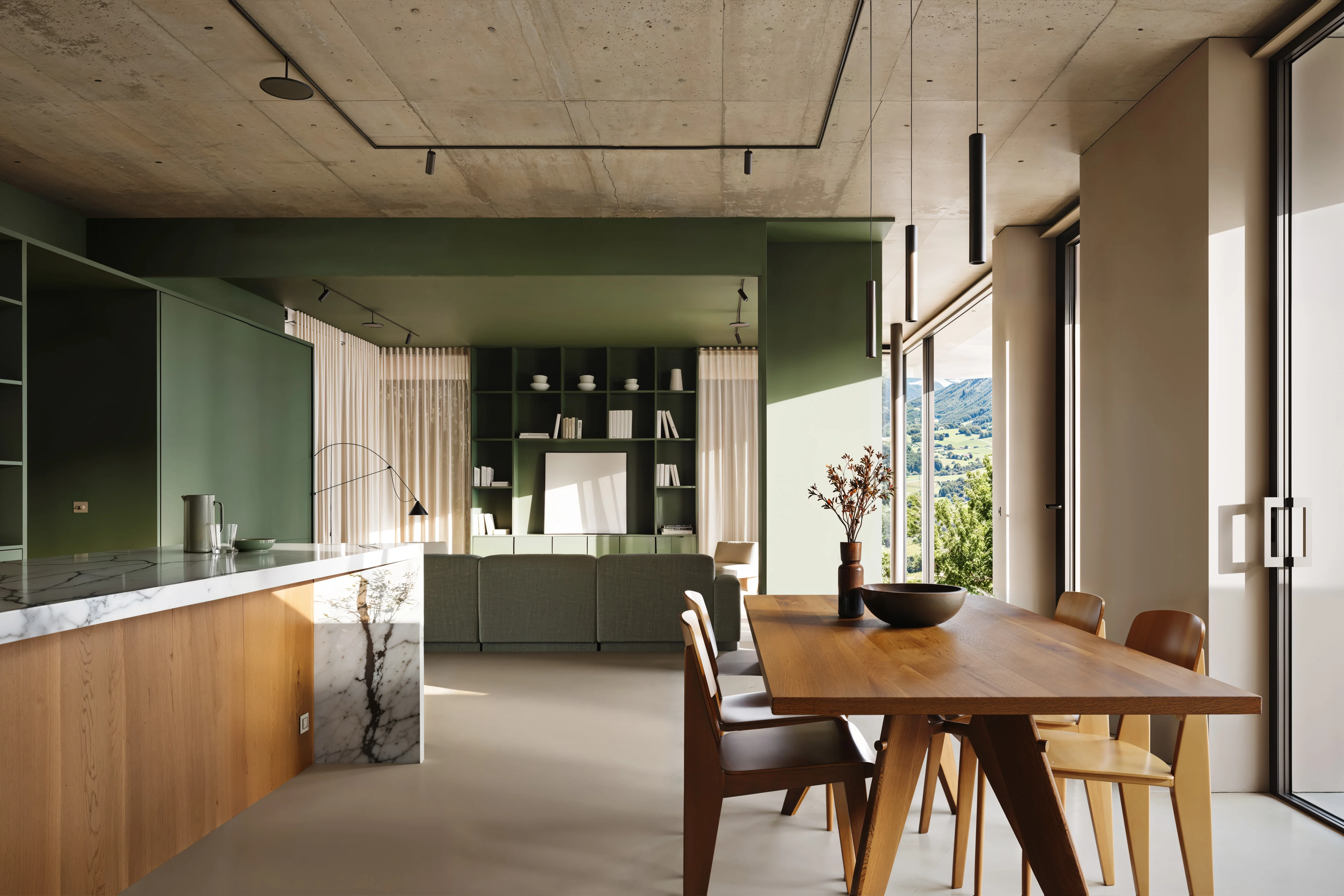 Modern open-plan living and dining area with wooden table, chairs, green sofa, shelves, and large windows showing a scenic mountain view.