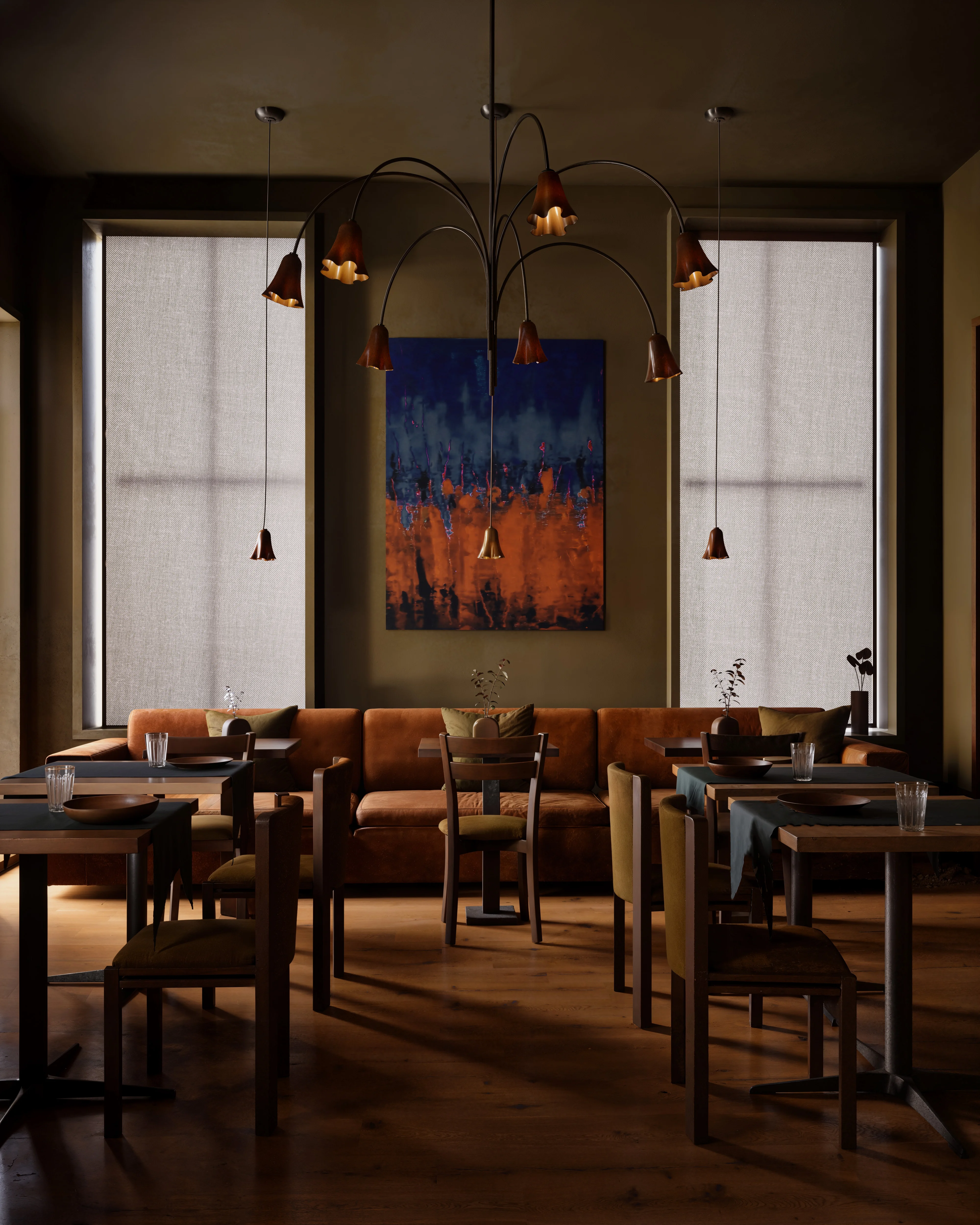 Cozy dining area with leather sofa, wooden tables and chairs, pendant lights, and abstract blue and orange painting between tall windows with blinds.