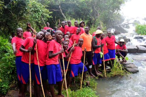 Group of teens with walking sticks between forest and river.