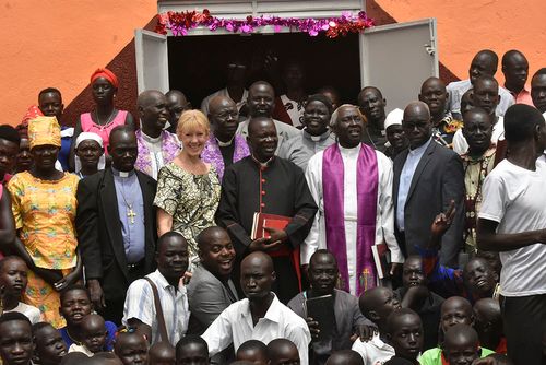 Carole and church group posing for a photo in front of their new church building.