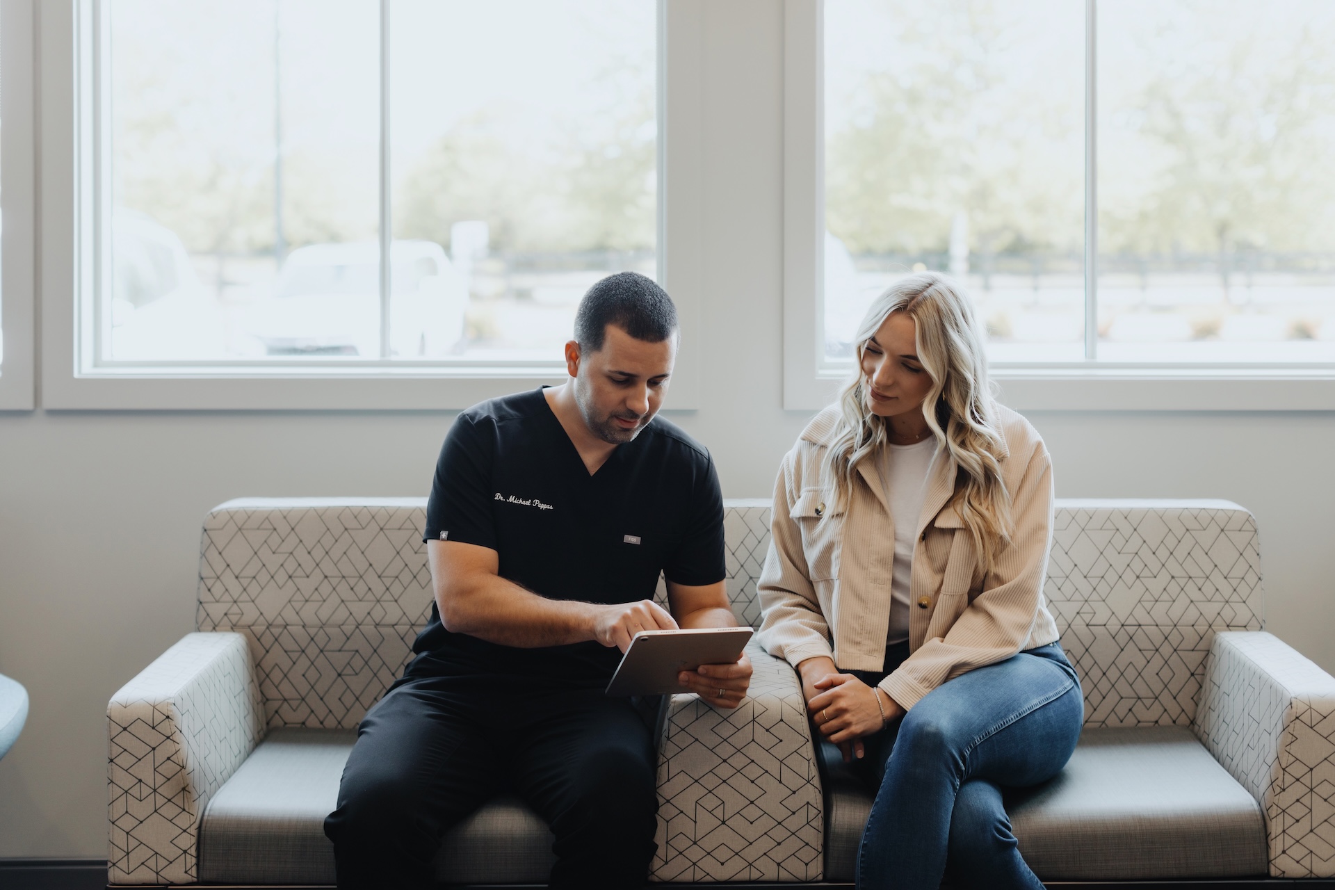 Dentist reviews treatment plan on tablet with patient in waiting area
