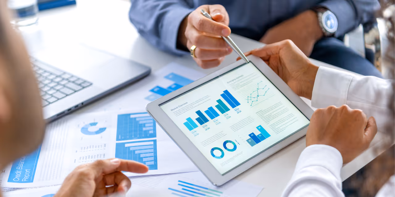 Business professionals reviewing financial charts and reports on a tablet during a meeting
