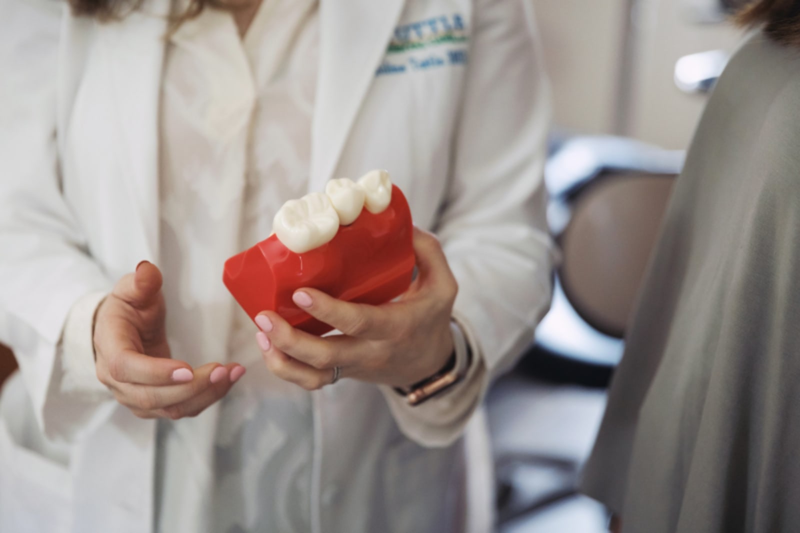 Dentist holding a red model of dental implants during patient consultation.