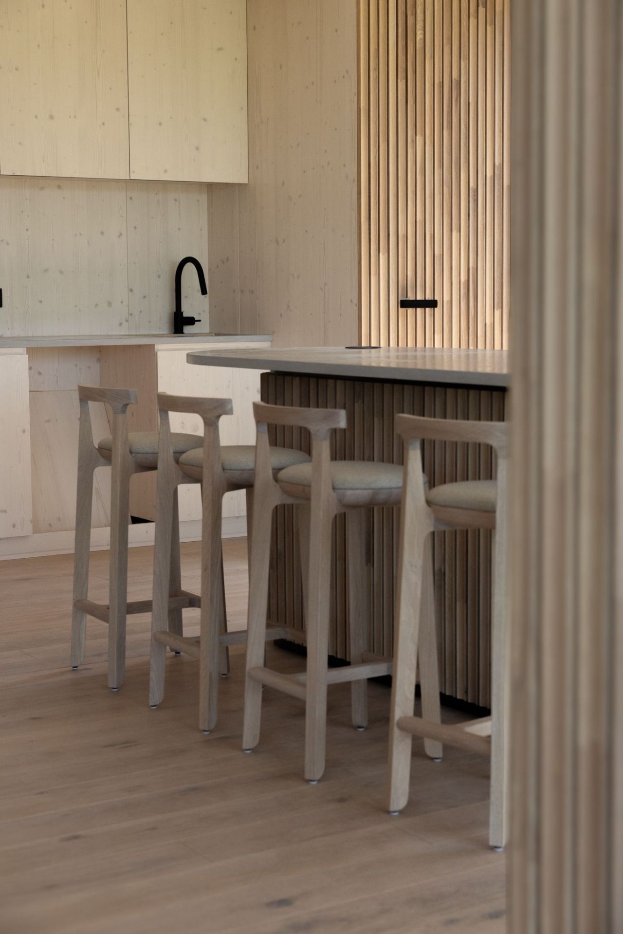 BeOak JURO tall bar stool with backrest, solid oak luxury furniture in a modern kitchen.