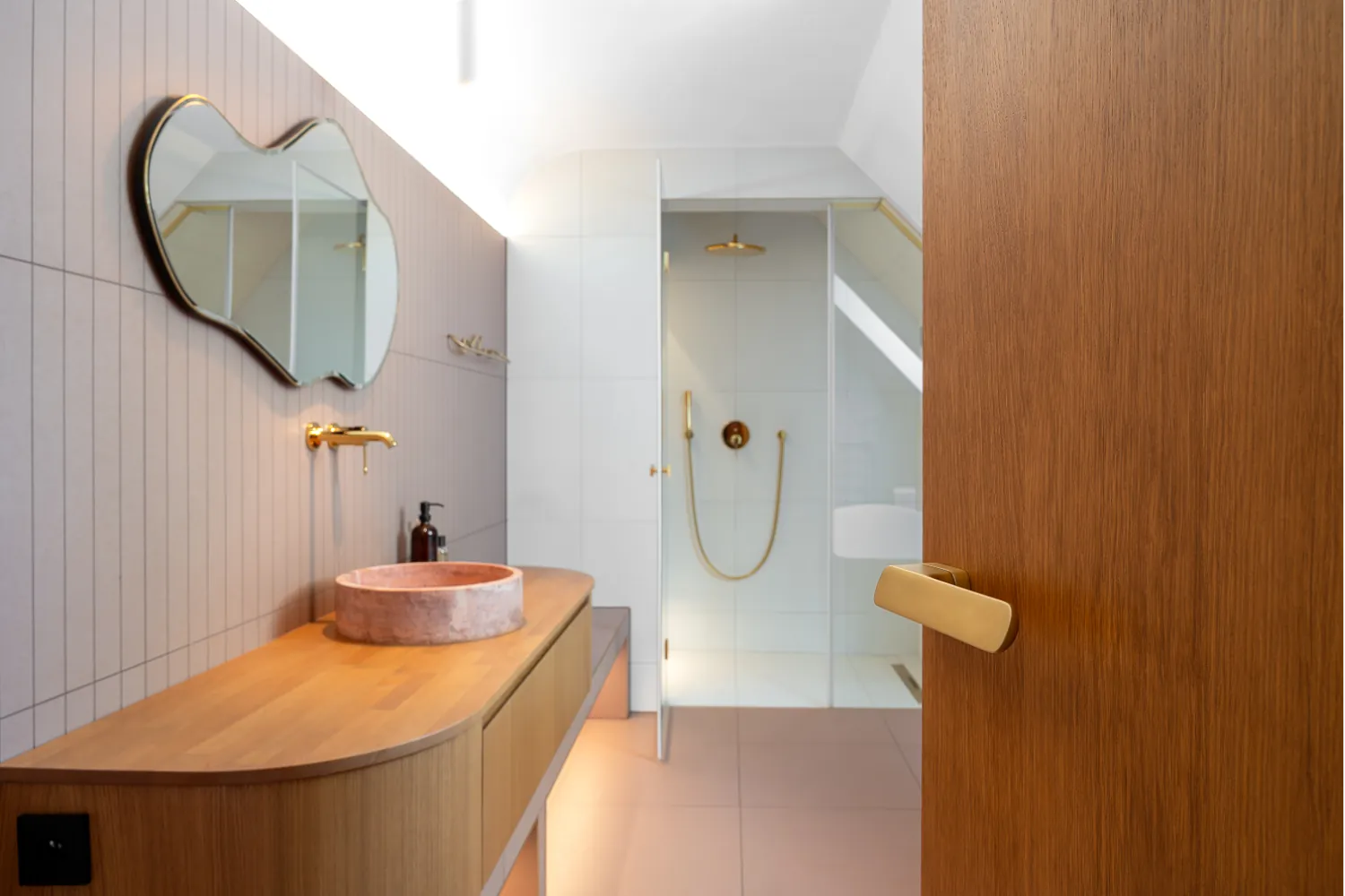 Bathroom with vertical gray tiles, roud vessel sink, wood veneer door with M&T Minimal 2.0 door handle in matte gold-like finish.