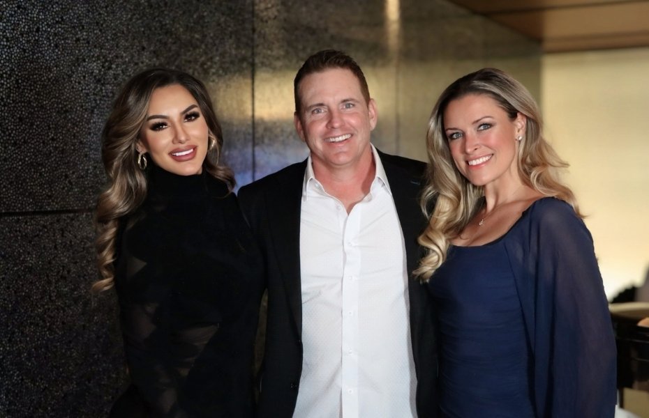 Venessa Patino poses with two guests, a man in a suit and a woman in a navy dress, during Adam S. Kutner’s Holiday Party at Red Rock Casino.