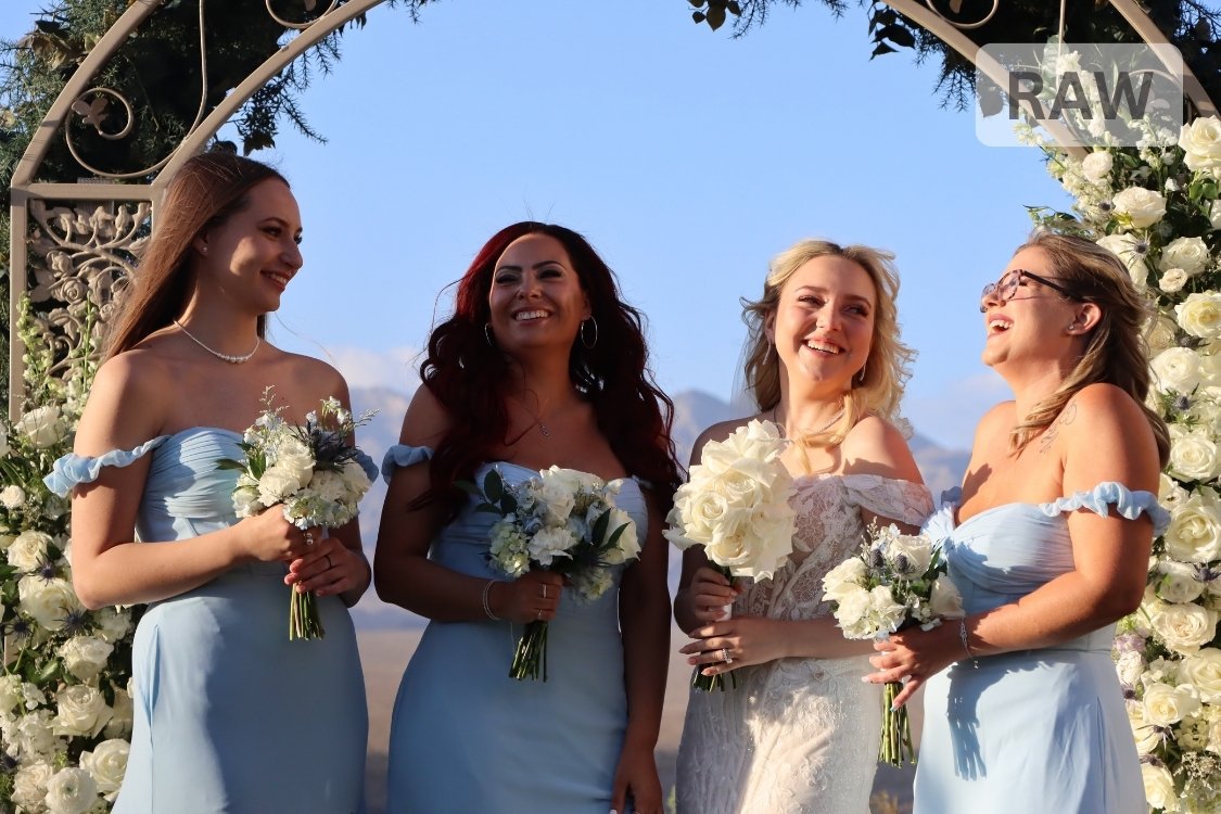 Bridesmaids in light blue off-shoulder dresses hold white bouquets, smiling together before the Paiute Golf Course ceremony.