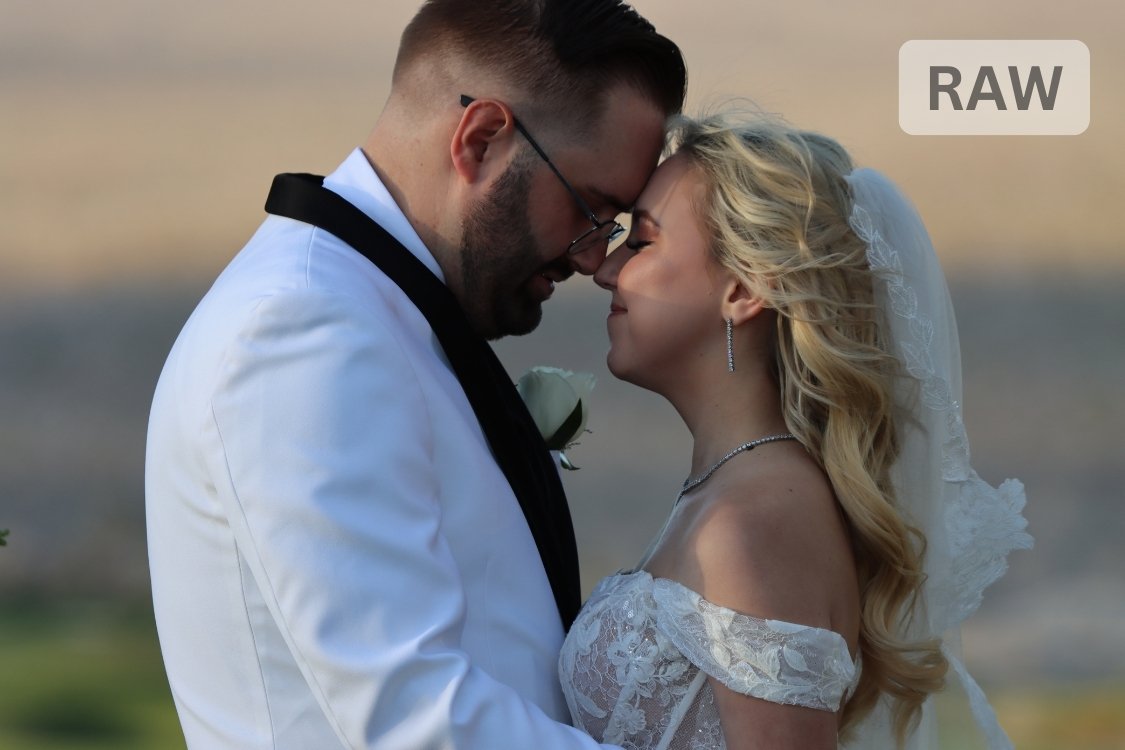 Bride and groom share a forehead-to-forehead moment, she in her flowing lace gown with curled hair, he in a crisp white tuxedo jacket, under the warm desert light.