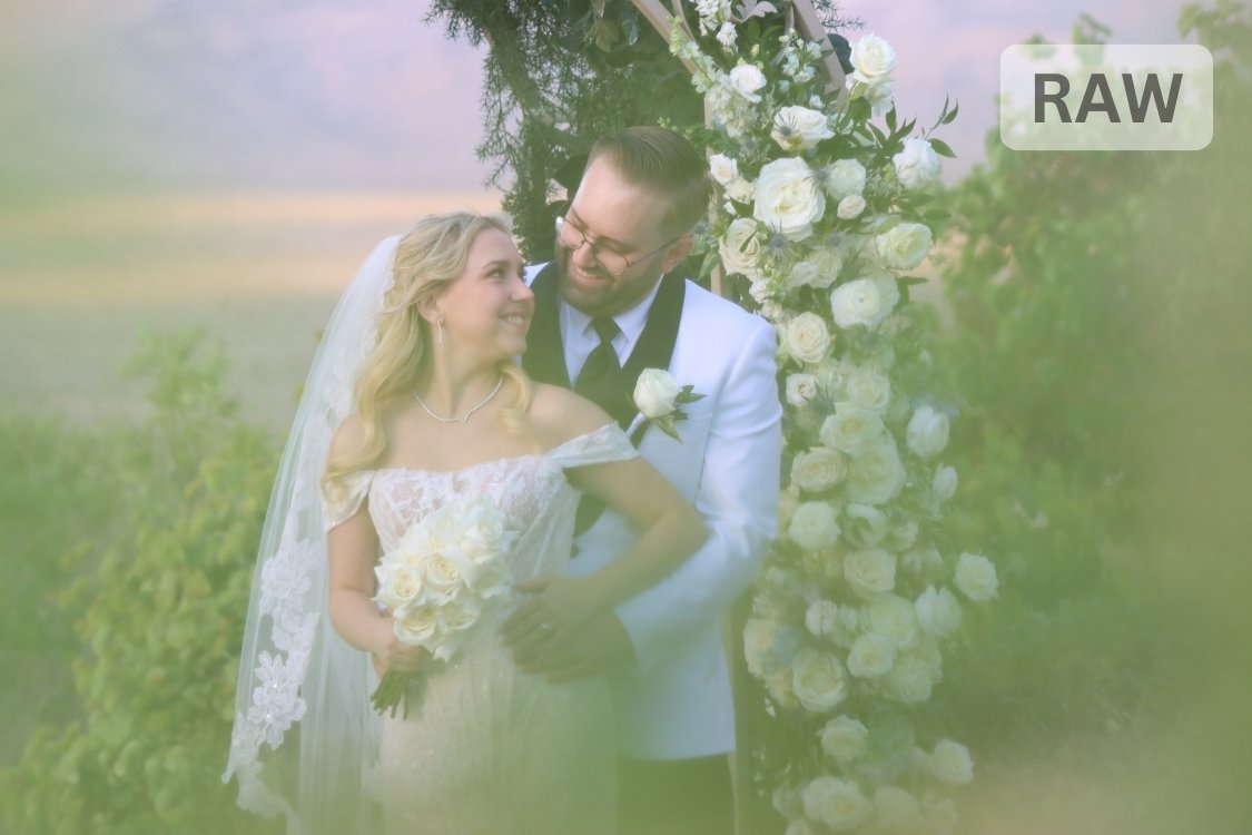 Romantic portrait of bride and groom embracing under a lush floral arch, bride’s veil flowing as they stand on the Paiute Golf Course lawn with mountain views behind.