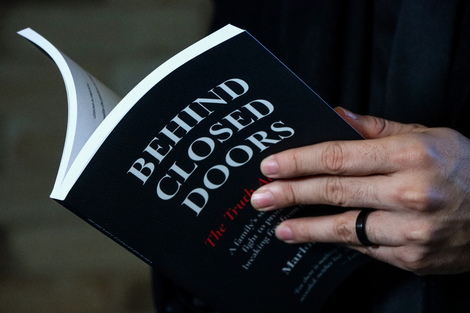 Close-up of hands holding Behind Closed Doors while reading