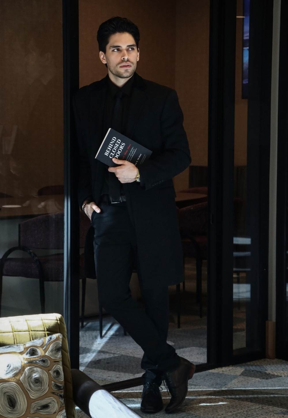 Author standing indoors holding Behind Closed Doors