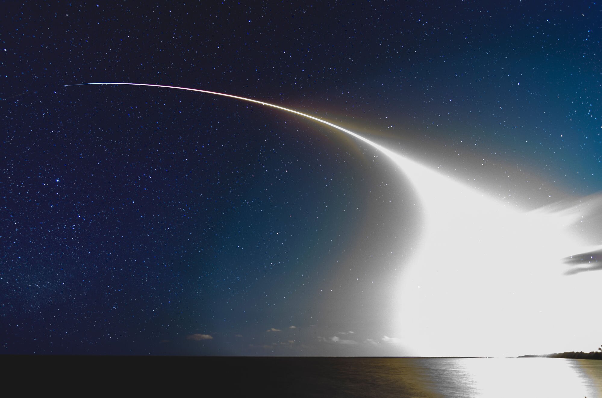 SpaceX rocket launch light trail over the ocean at night