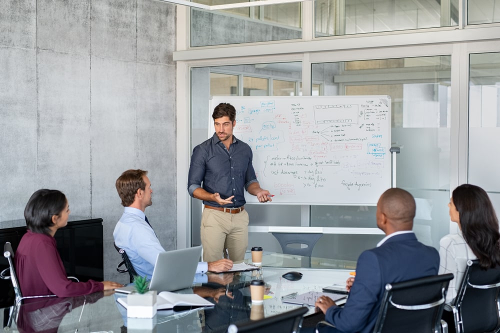 A manager delivering a presentation to colleagues around a boardroom table