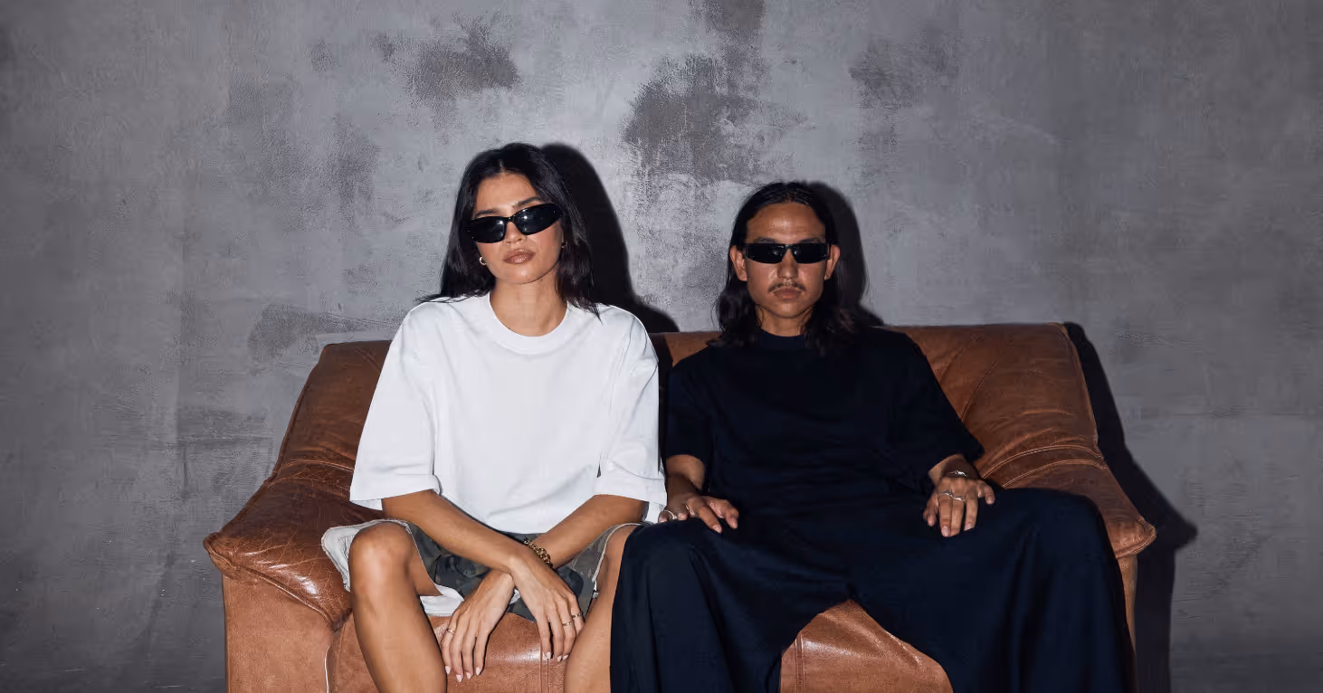 models in studio on brown leather couch in front of concrete wall