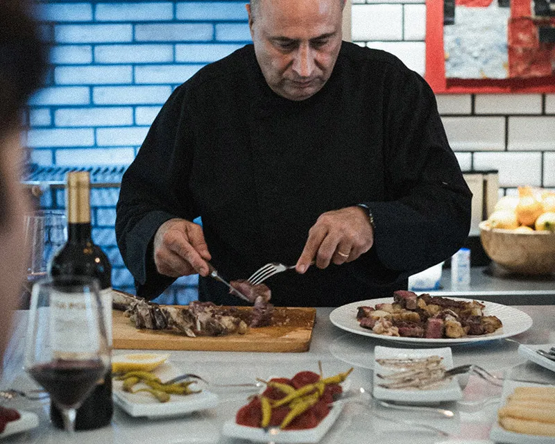 Cuiner tallant carn a la brasa a l'illa de la cuina